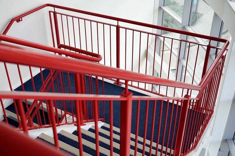 A multi-level staircase with red-painted metal railings