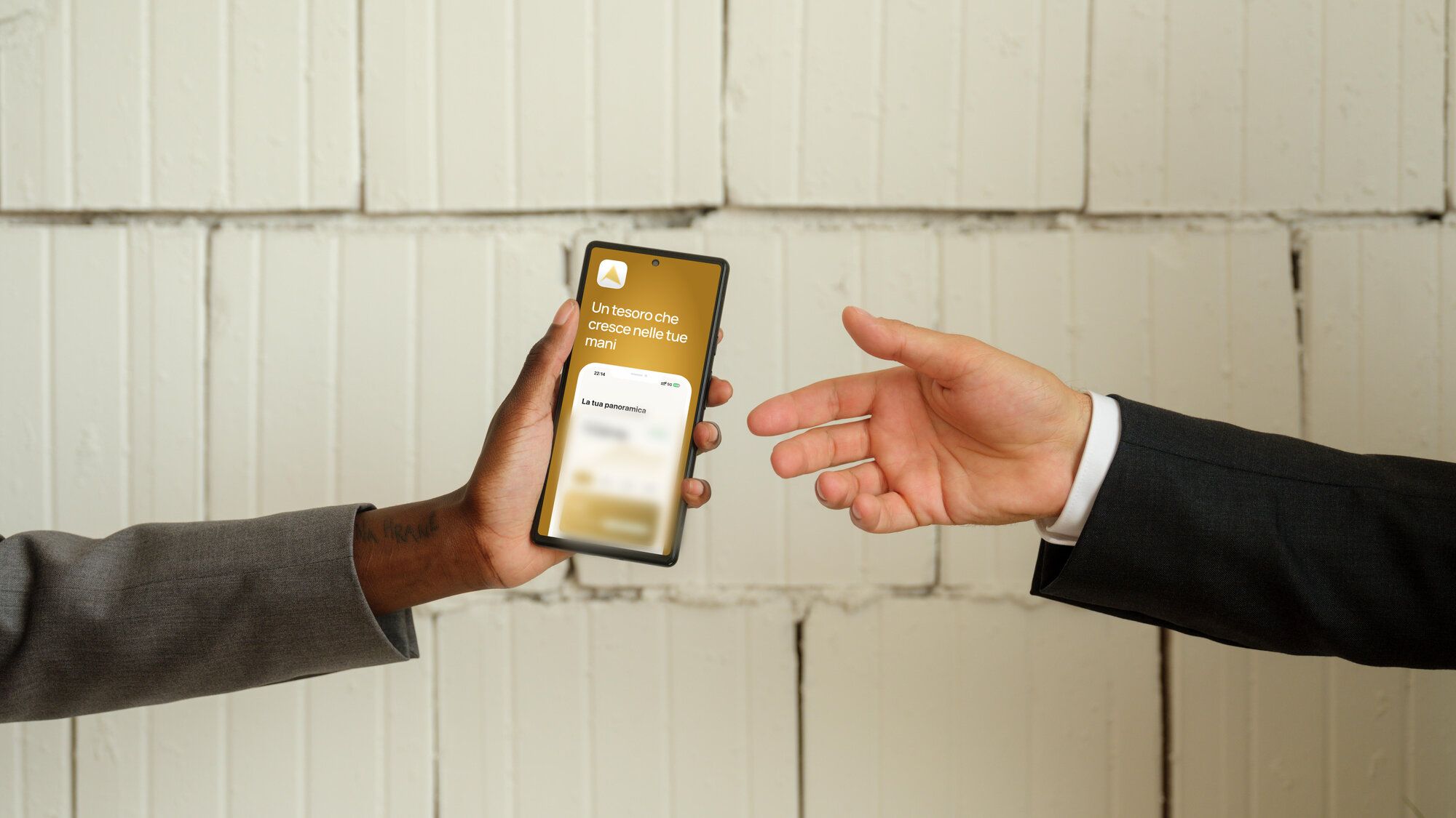 Due mani si passano uno smartphone con l'app Aurelia Gold aperta sulla schermata di benvenuto