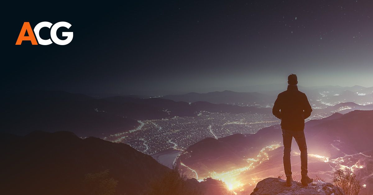 Dark image of a man overlooking a city of lights in the mountains