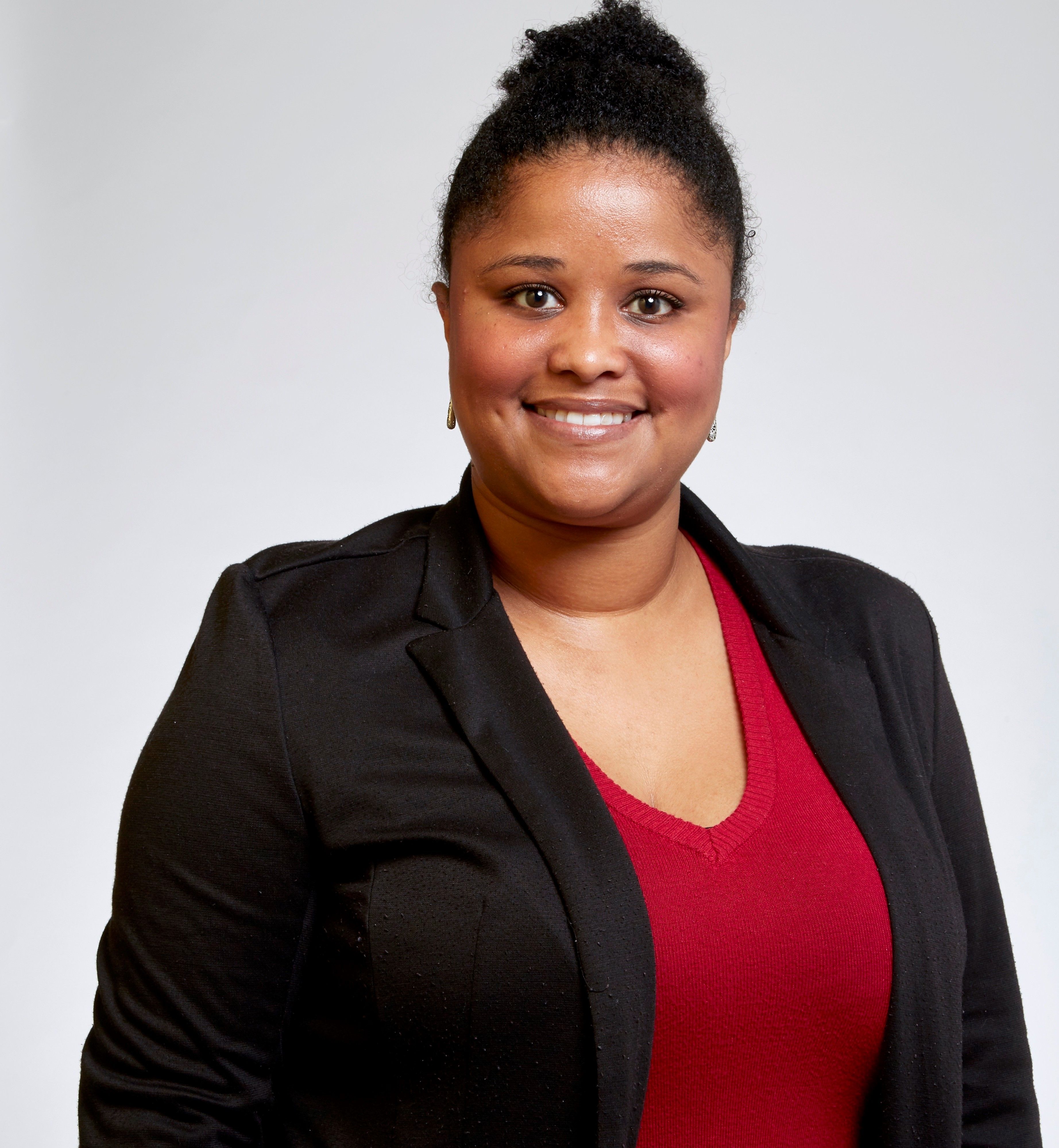 Portrait showing a smiling black woman wearing a red shirt and a black suit jacket.