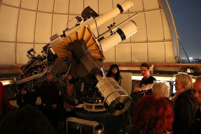 Picture showing the inside of a star dome on a clear night with people gathered around the telescope