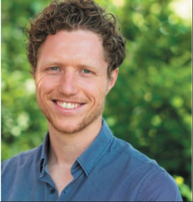 Portret van een glimlachende man met donkerblonde krullen