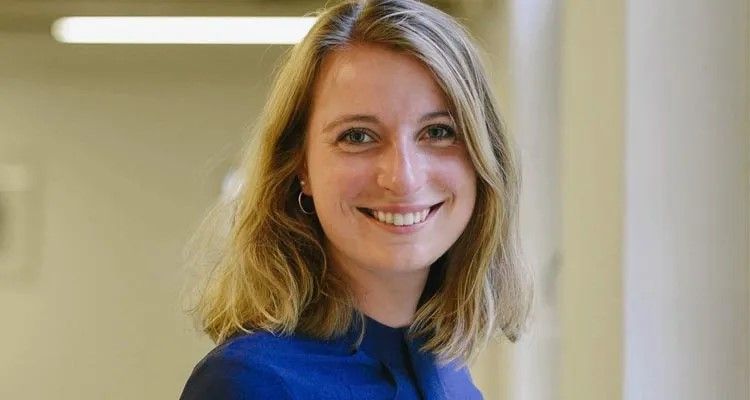 Portret van een lachende jonge vrouw met blond haar en een blauw shirt