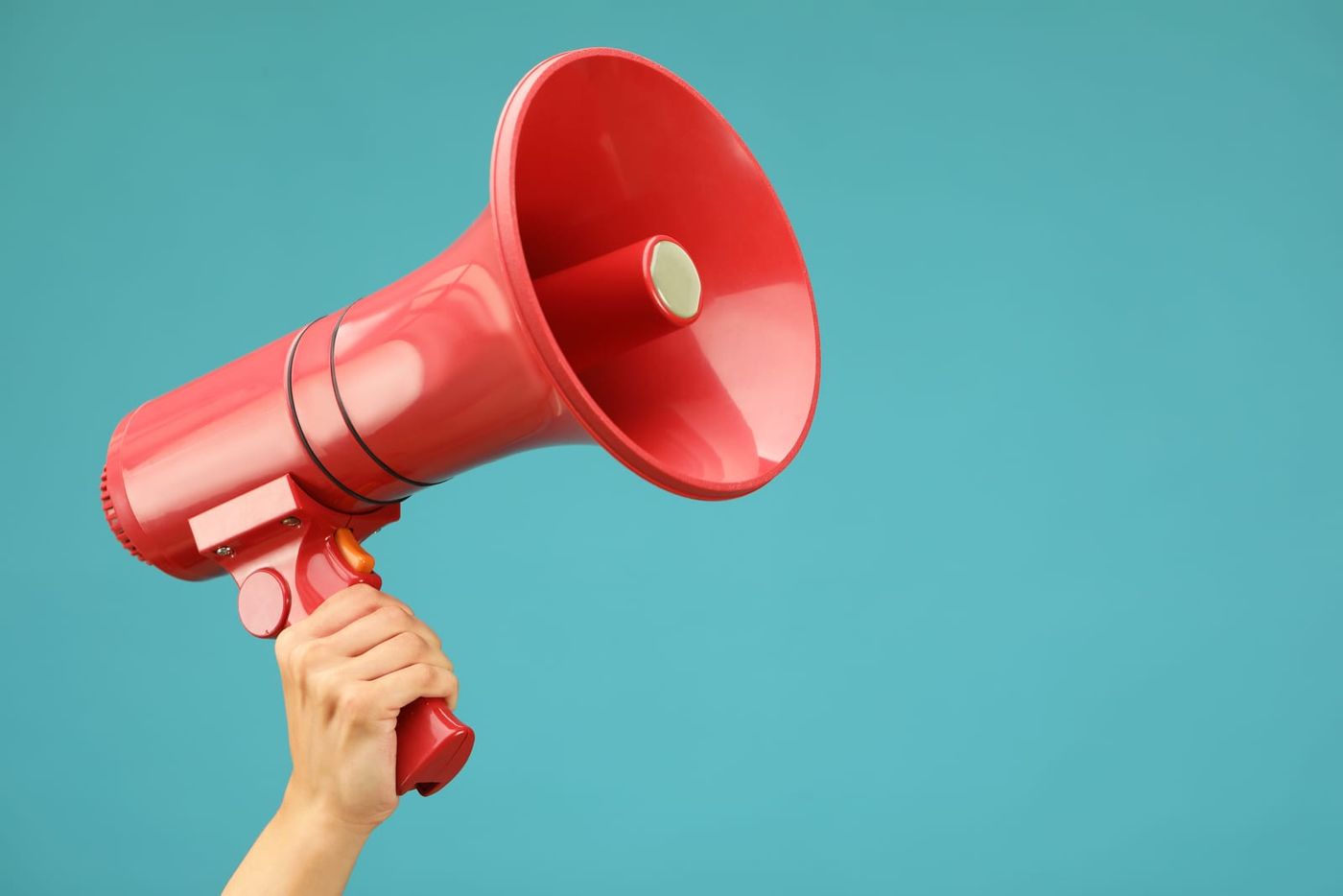 A hand holding a red megaphone against a teal background