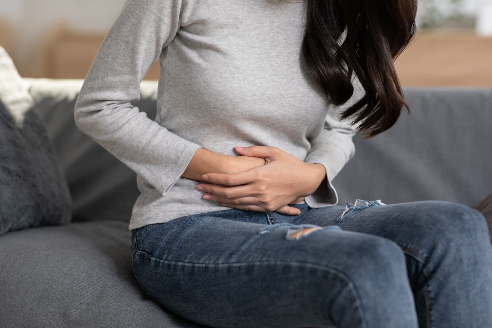 lady in gray long sleeves holding the abdomen