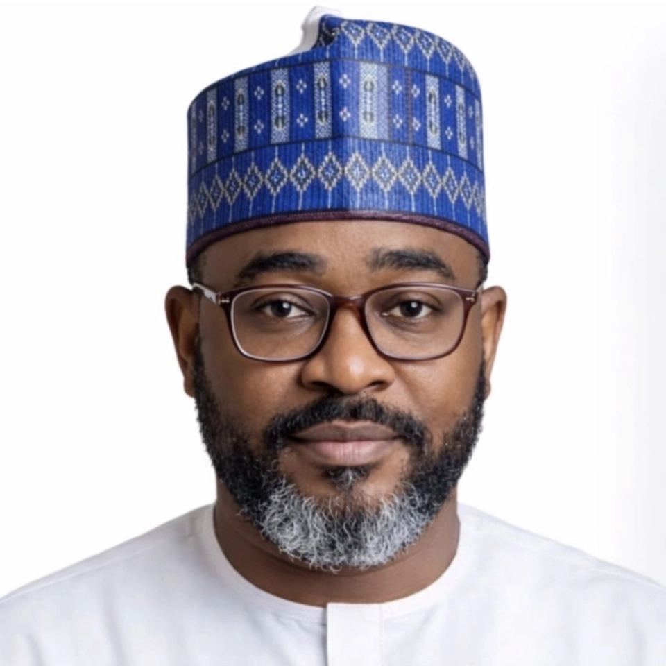 Formal head-and-shoulders portrait of a man wearing glasses, a blue patterned cap and white attire.