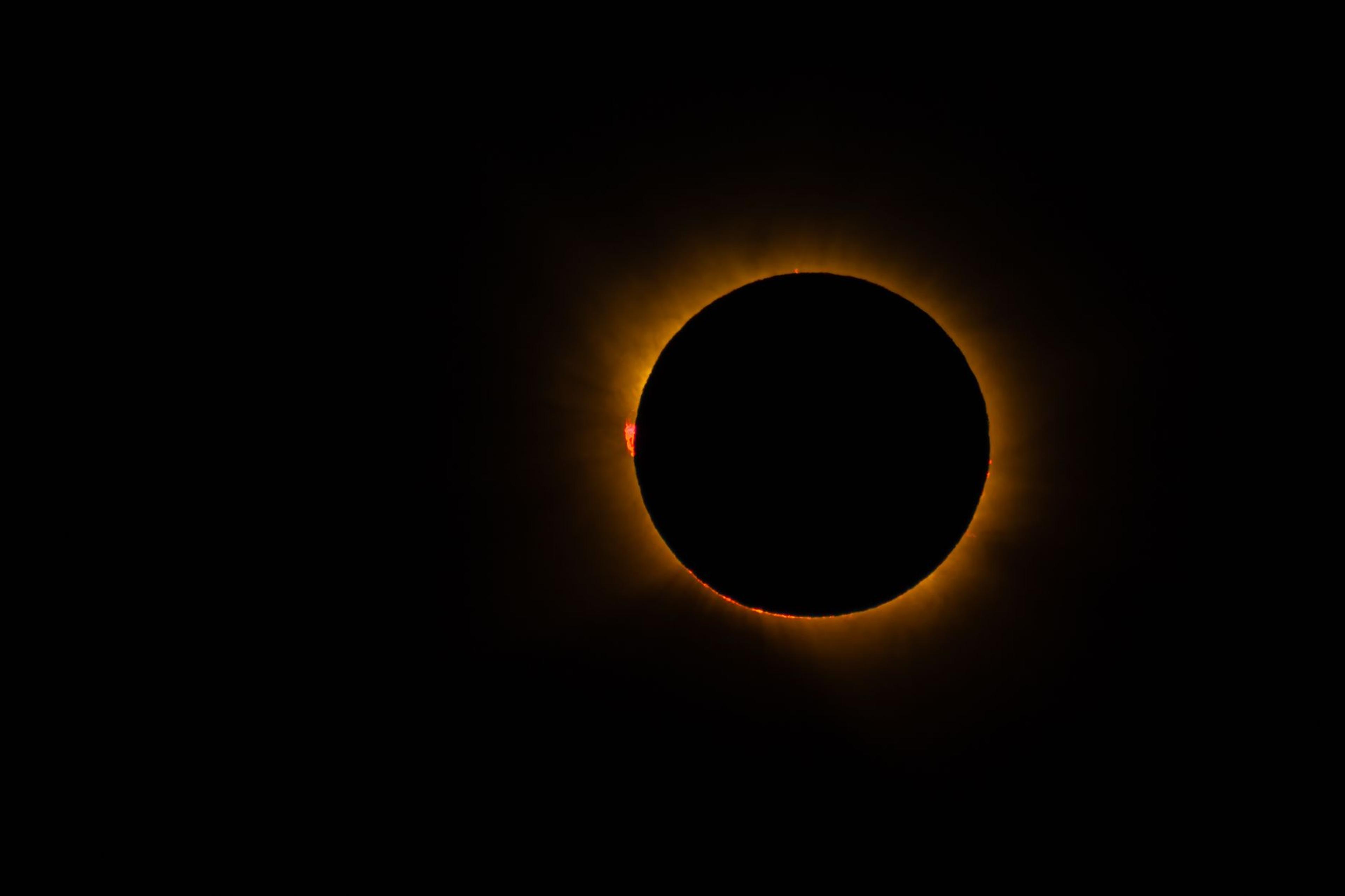 A total solar eclipse glowing with a bright corona against a darkened sky