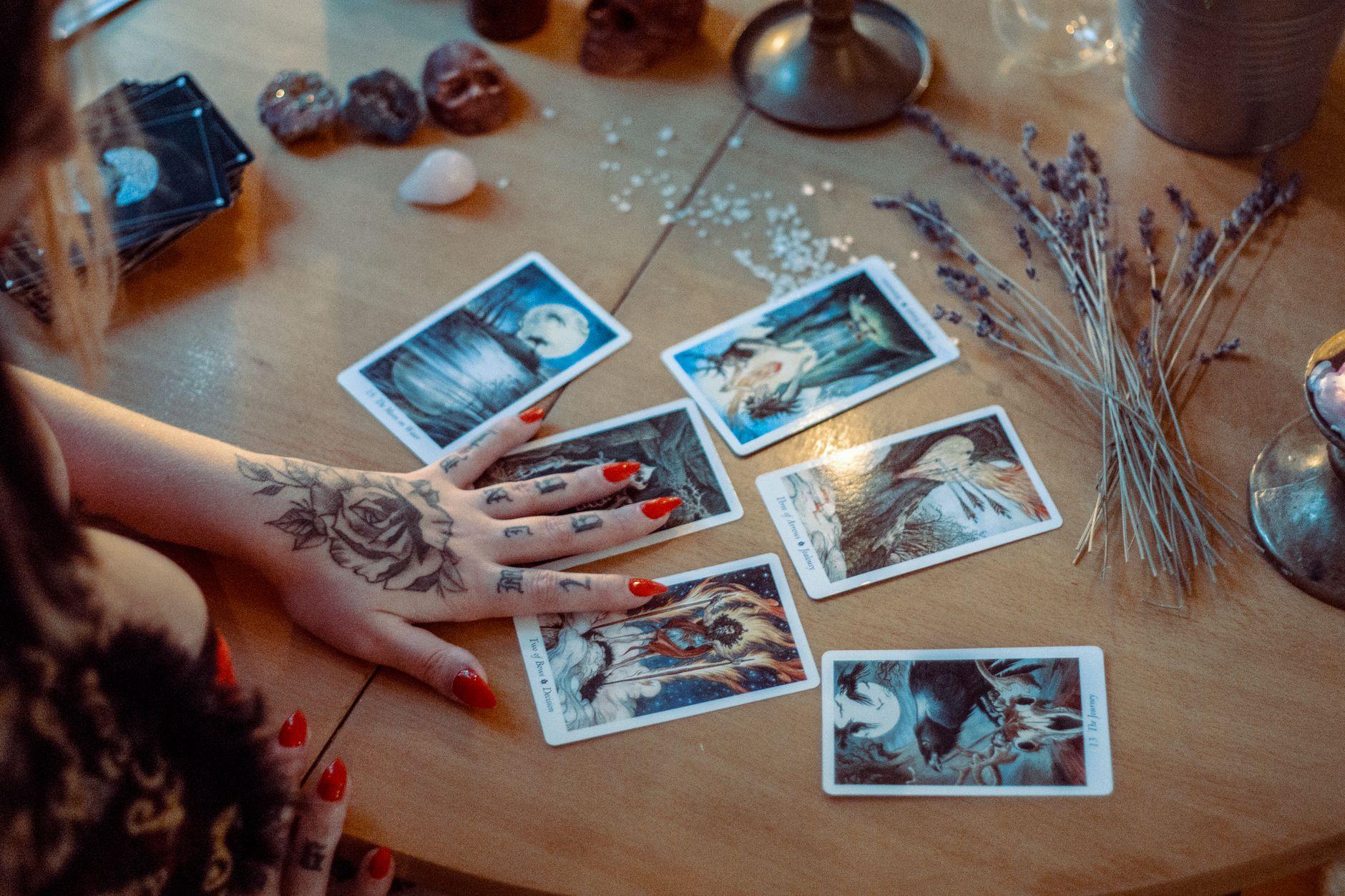 Tarot cards spread on a wooden table with dried flowers, evoking growth and renewal