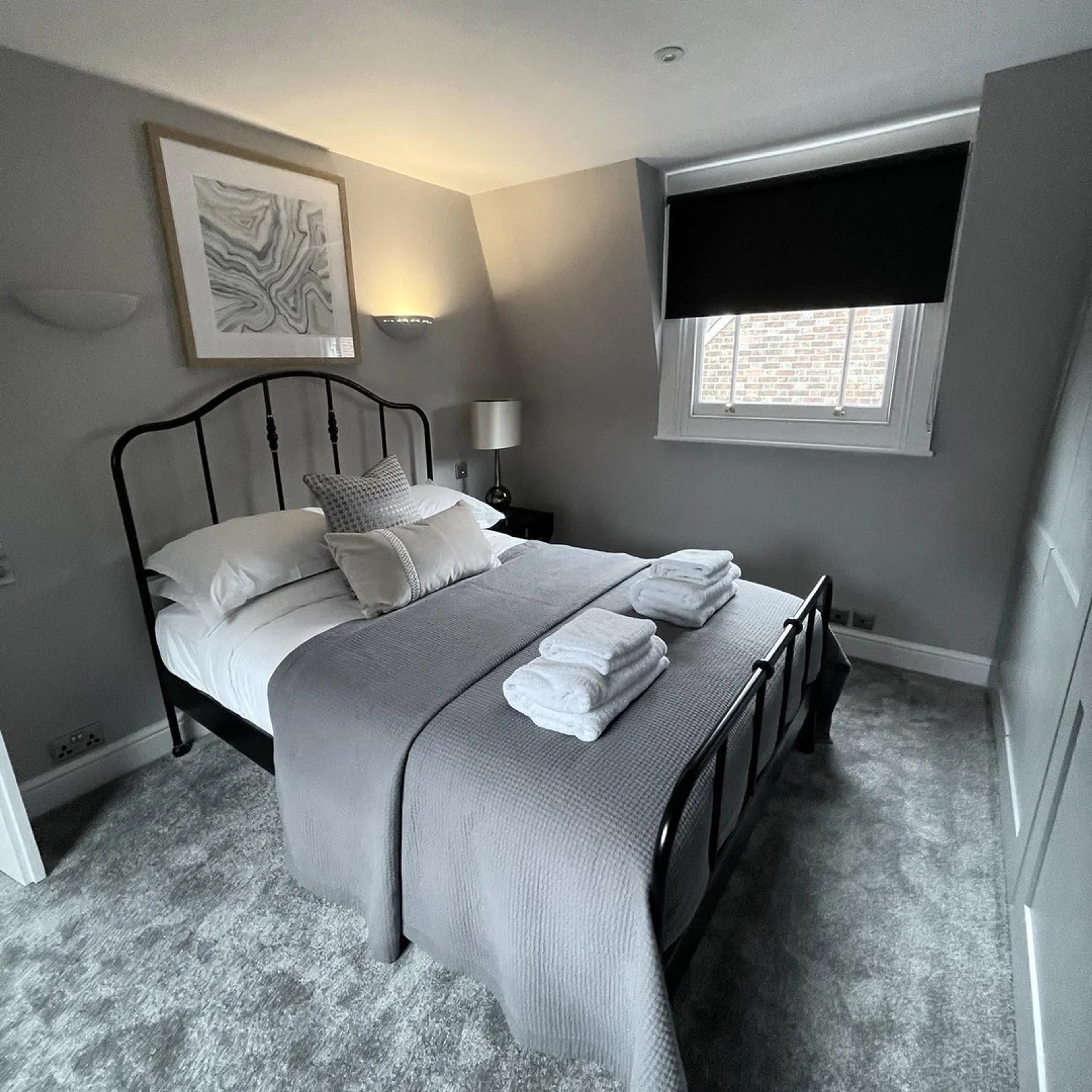 Modern bedroom in The House with grey decor and black metal bed frame