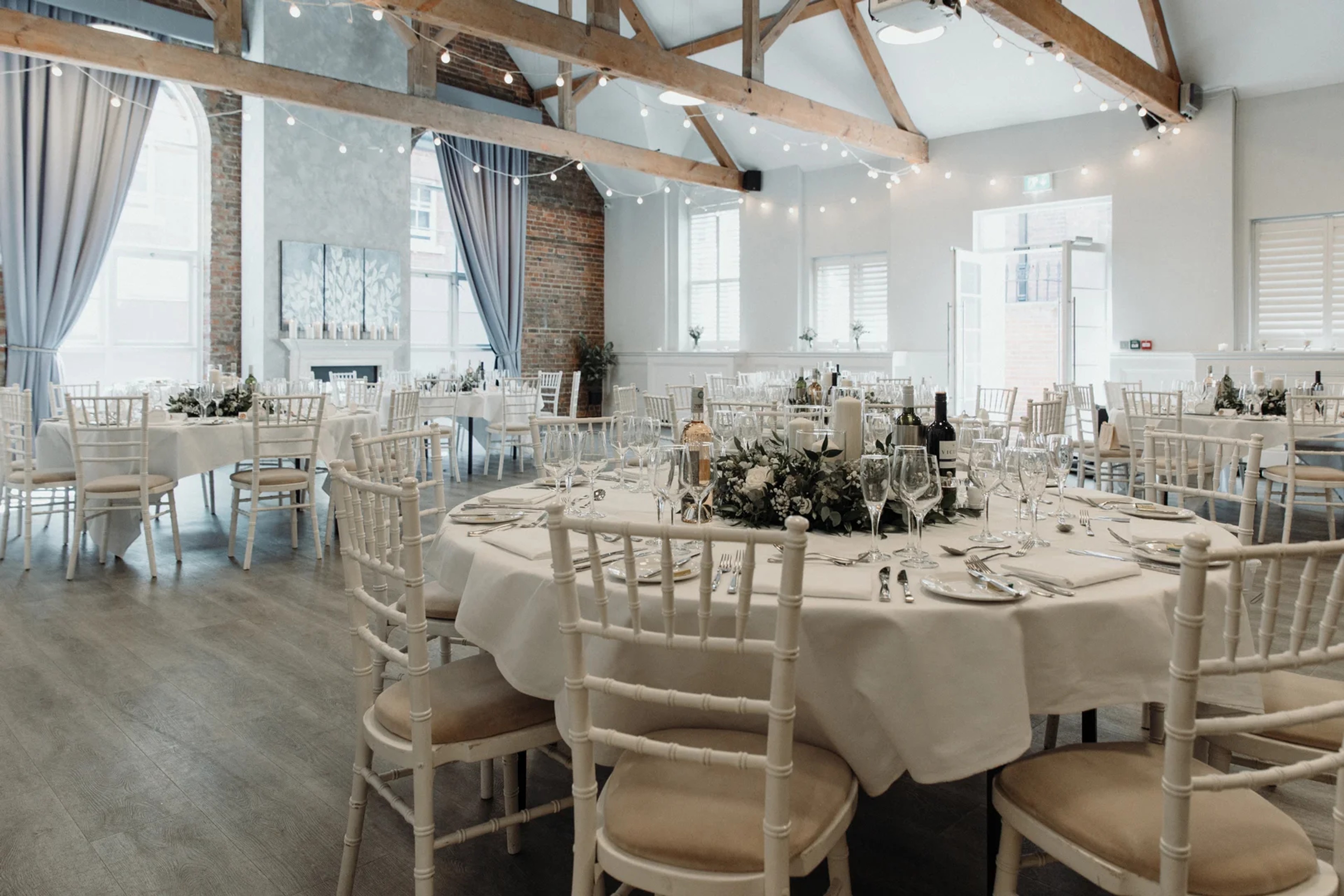 Wedding reception room with round tables, chiavari chairs and festoon lighting