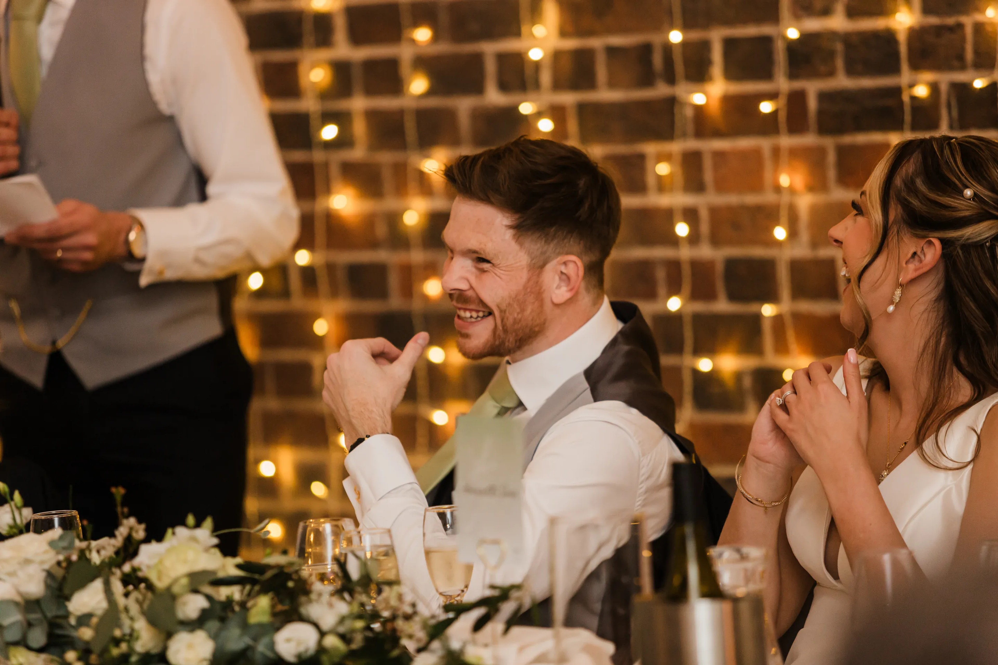 Bride and groom laughing during wedding speeches