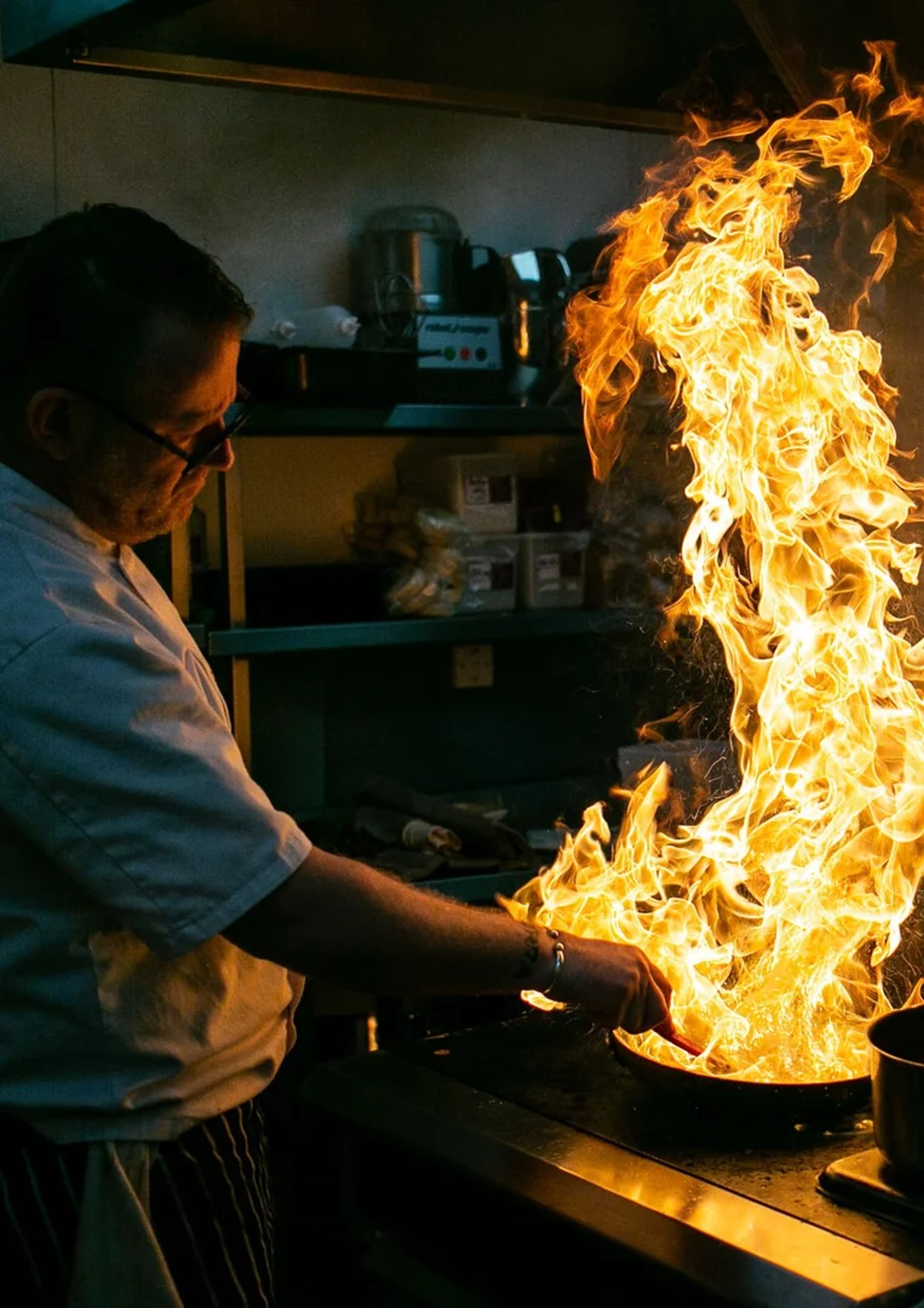 Chef cooking with dramatic flames in the kitchen at One Warwick Park