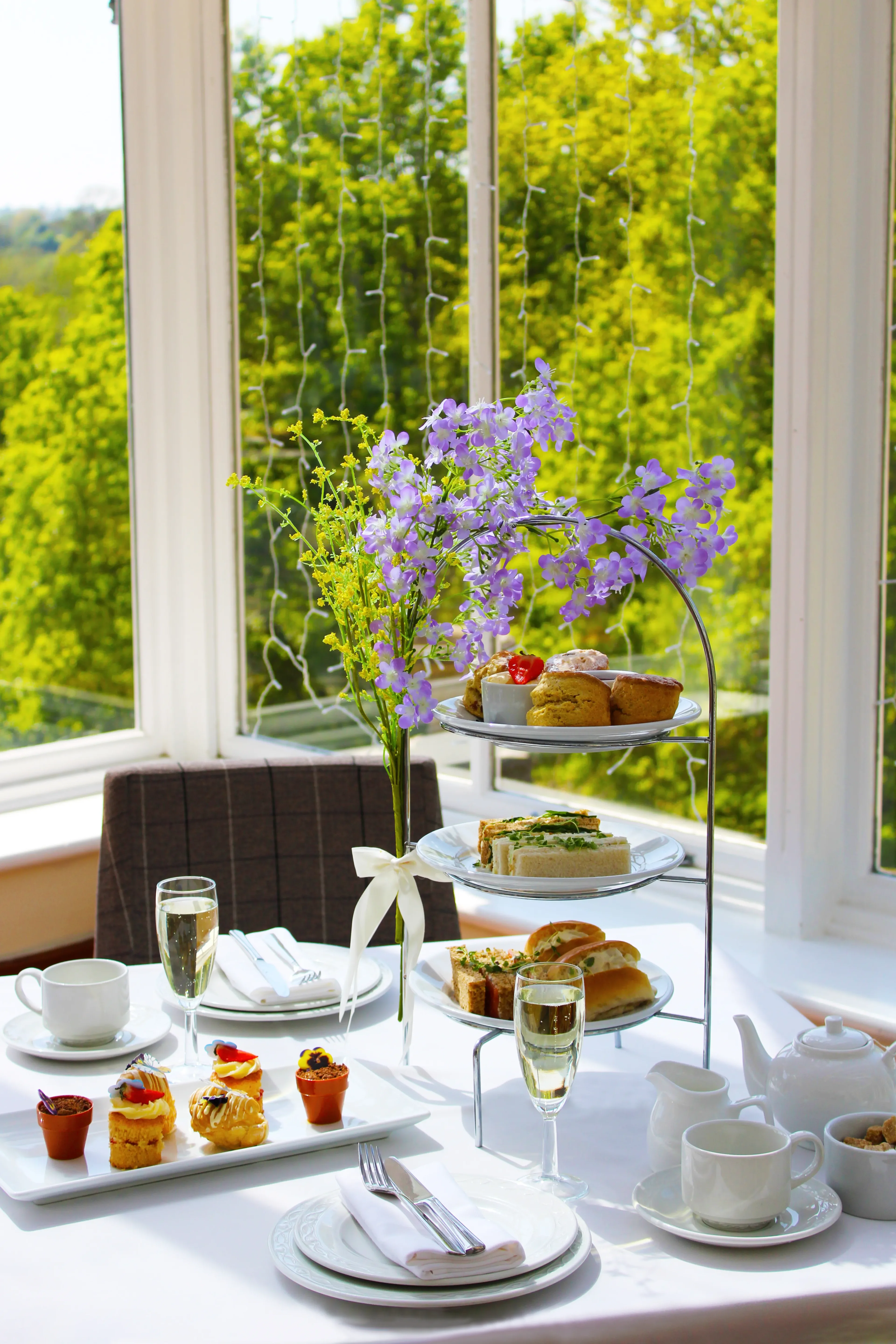 Afternoon tea spread with tiered stand, scones, and champagne by a sunlit window at Salomons Estate