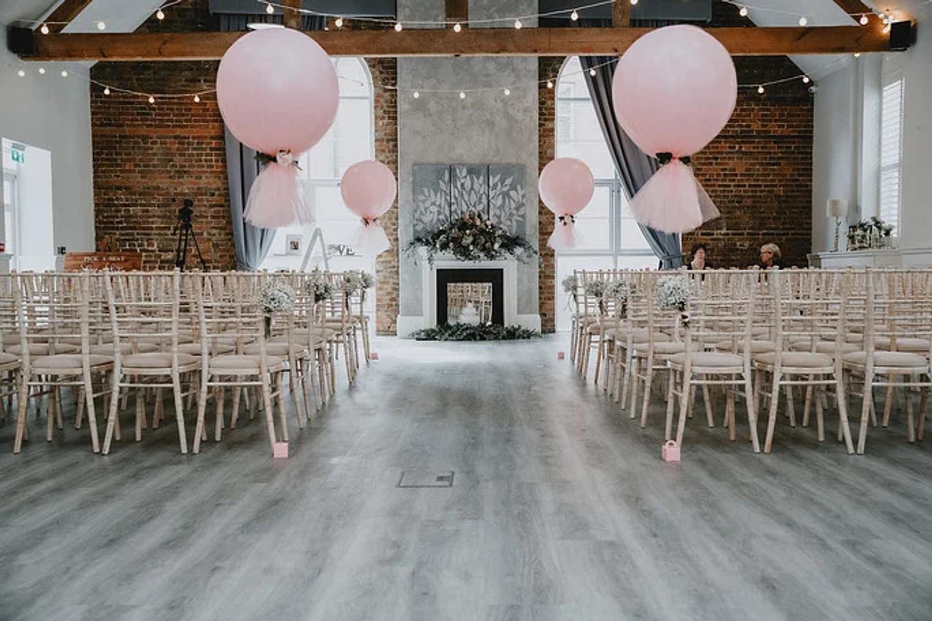 Wedding ceremony setup with pink balloon decorations and exposed brick walls