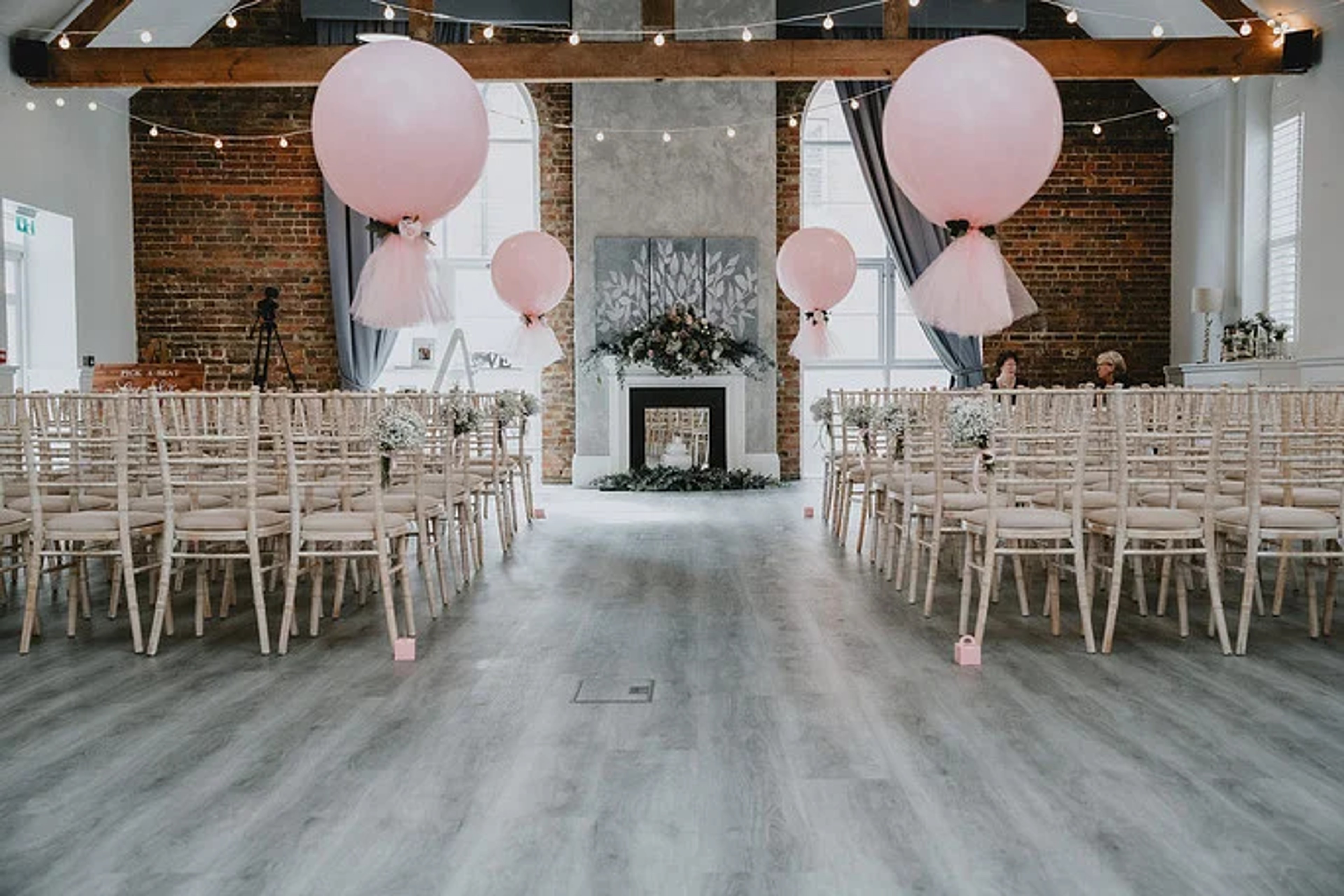 Wedding ceremony setup with pink balloon decorations and exposed brick walls