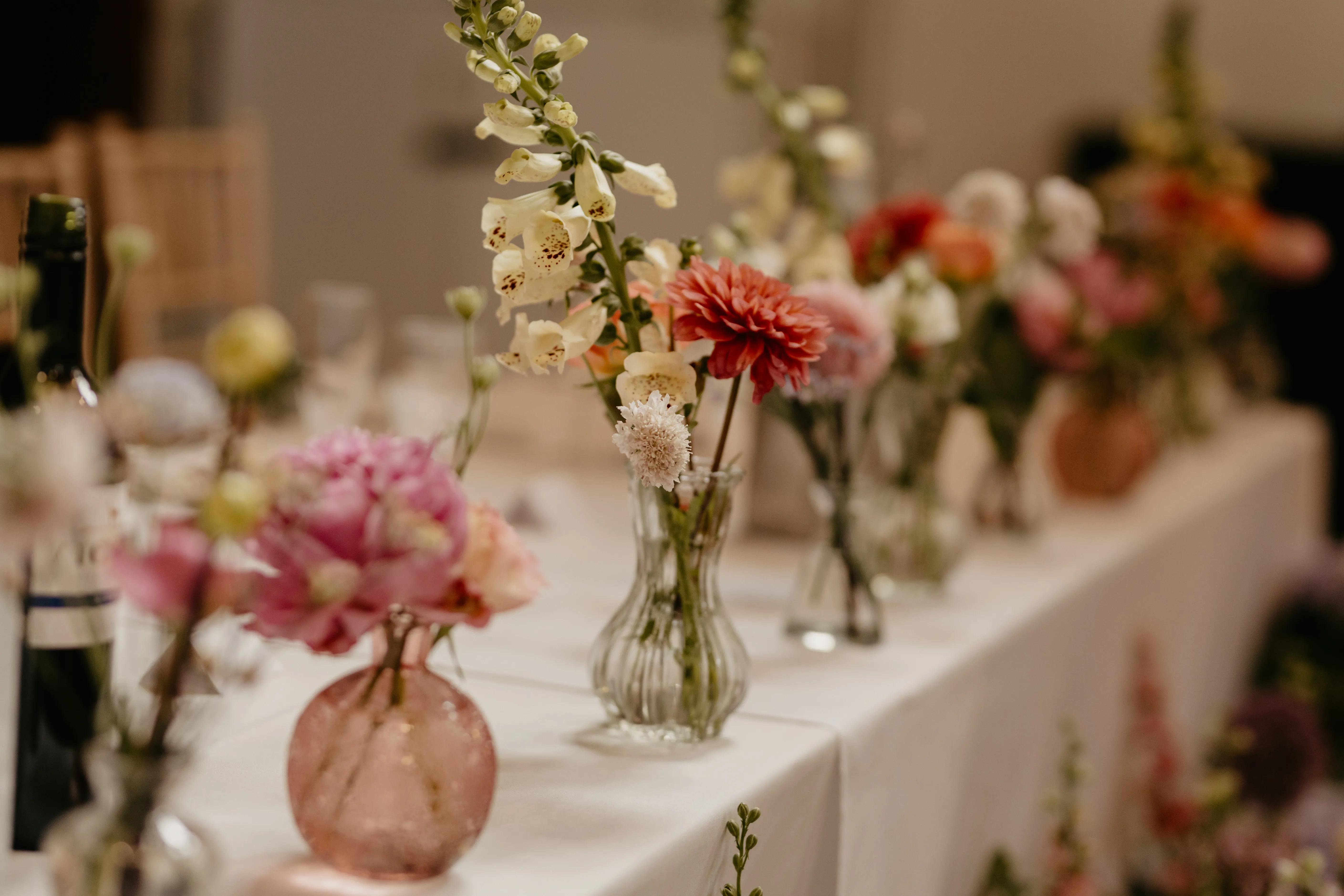 Colourful floral table decorations with vases at a celebration at Salomons Estate