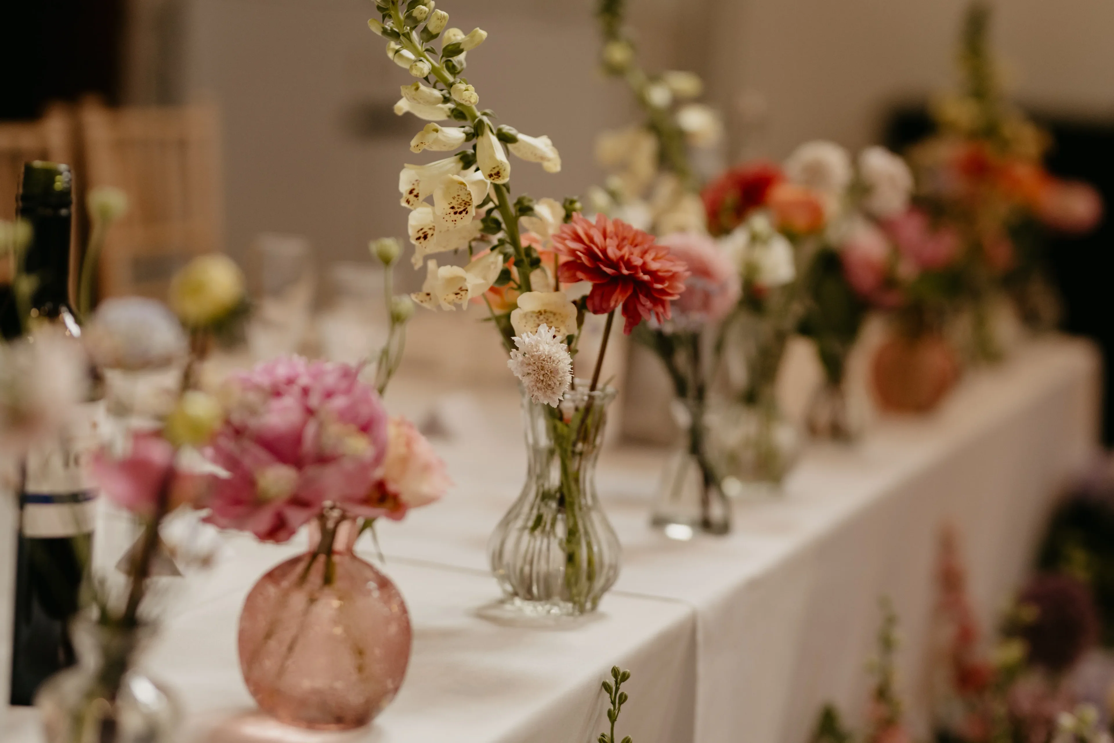 Colourful floral table decorations with vases at a celebration at Salomons Estate