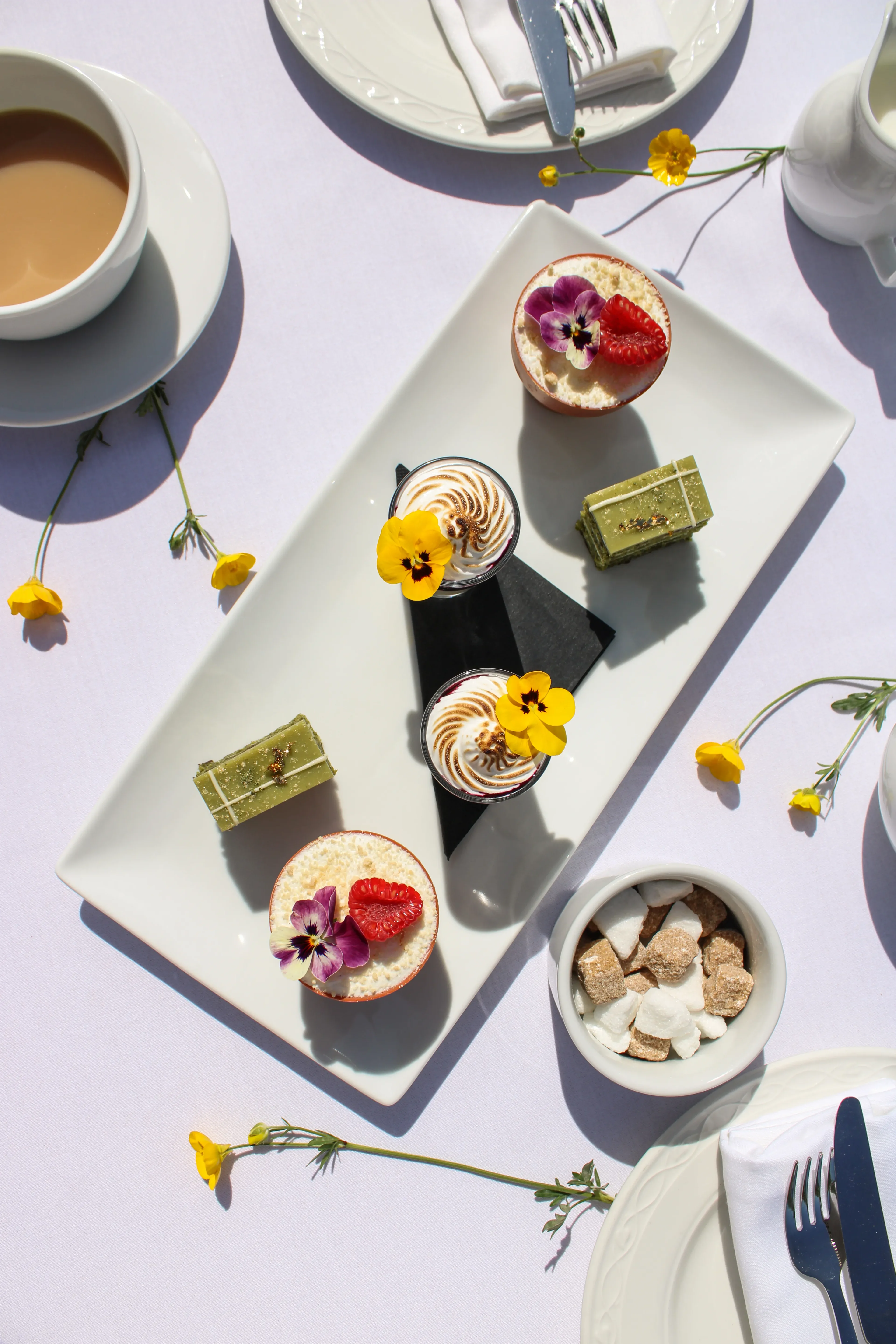 Overhead view of afternoon tea desserts with wildflowers and tea cups at Salomons Estate
