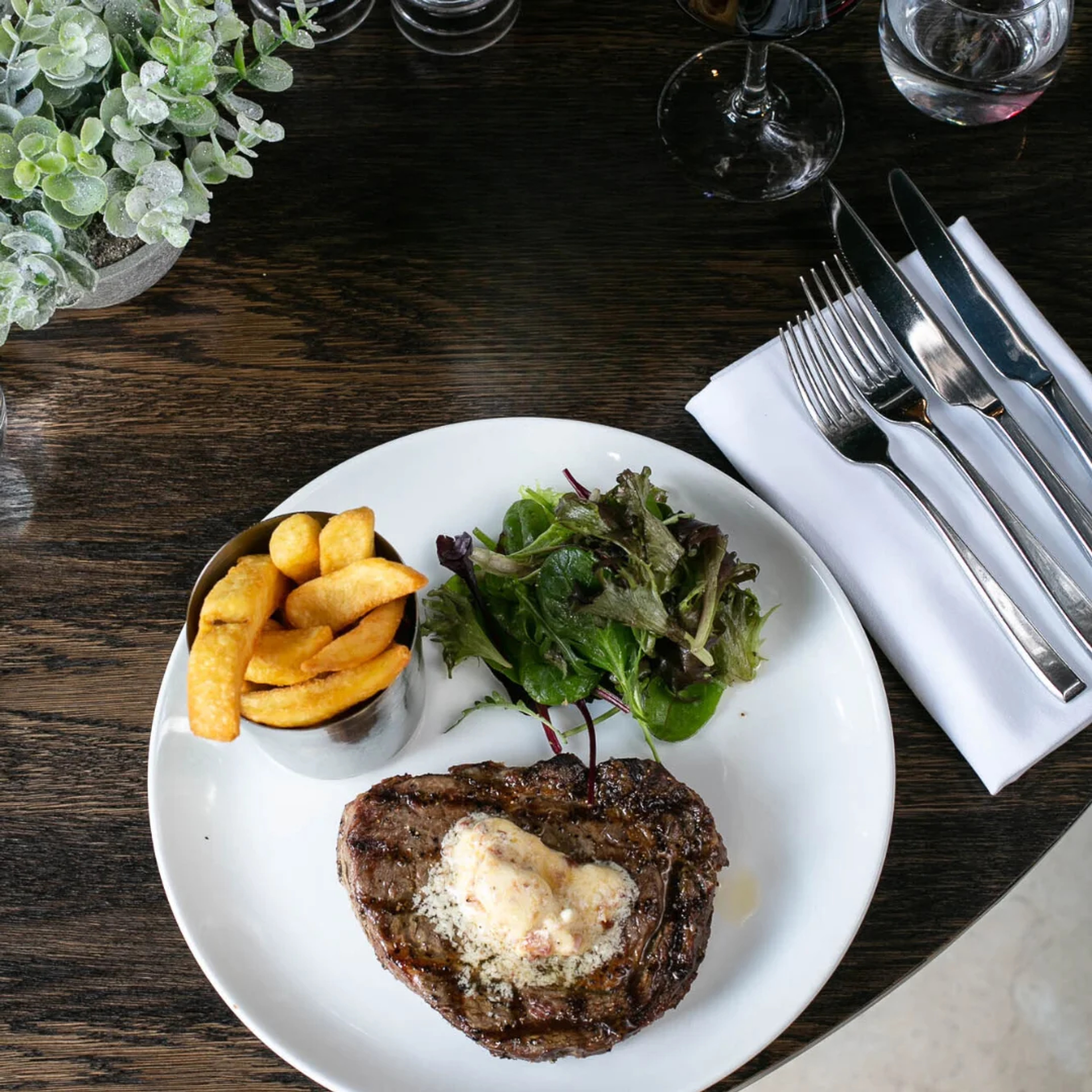 Perfectly cooked ribeye steak with herb butter, triple-cooked chips and salad