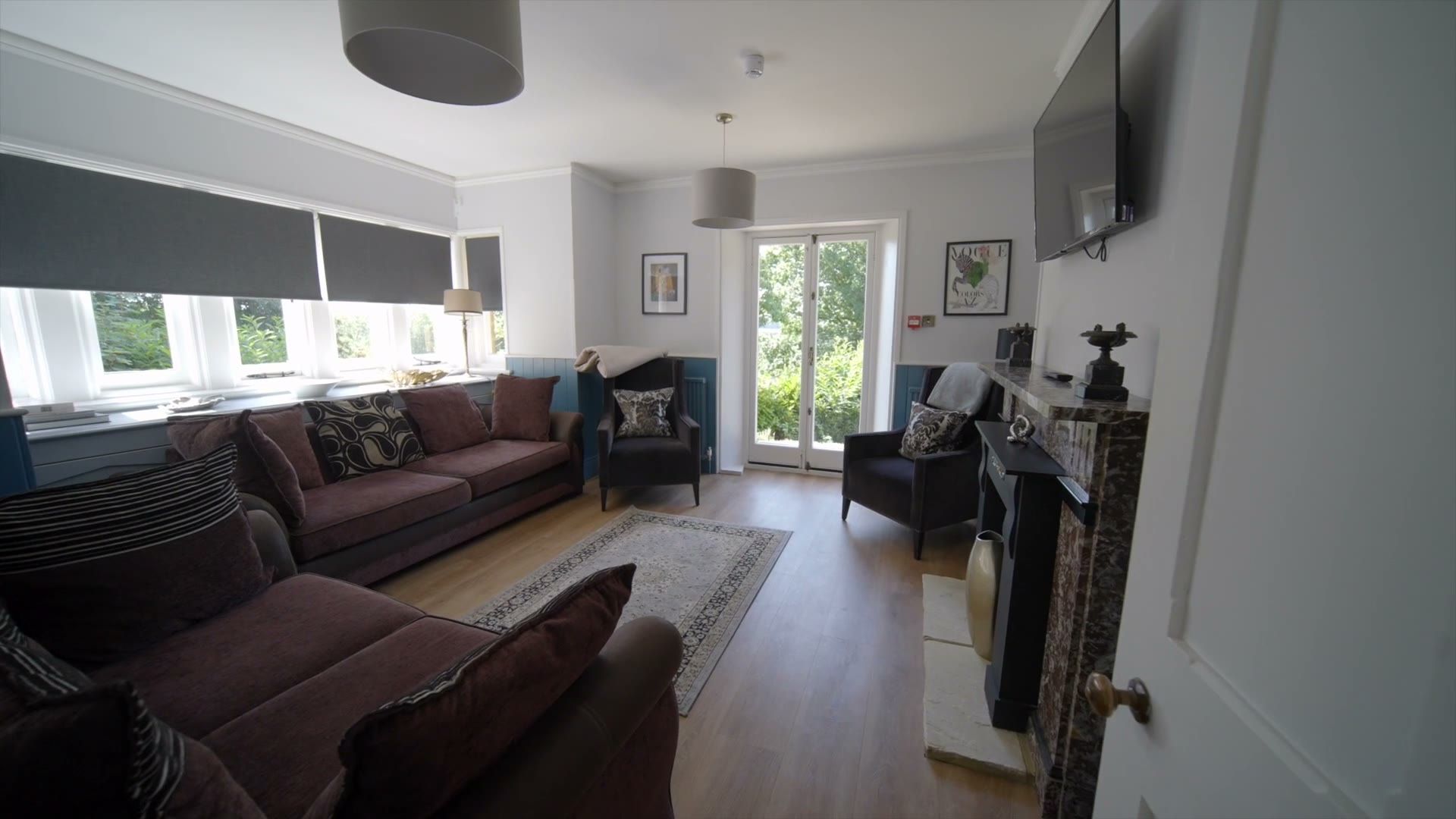 Lounge with sofas, fireplace and garden doors inside The Gatehouse at Salomons Estate
