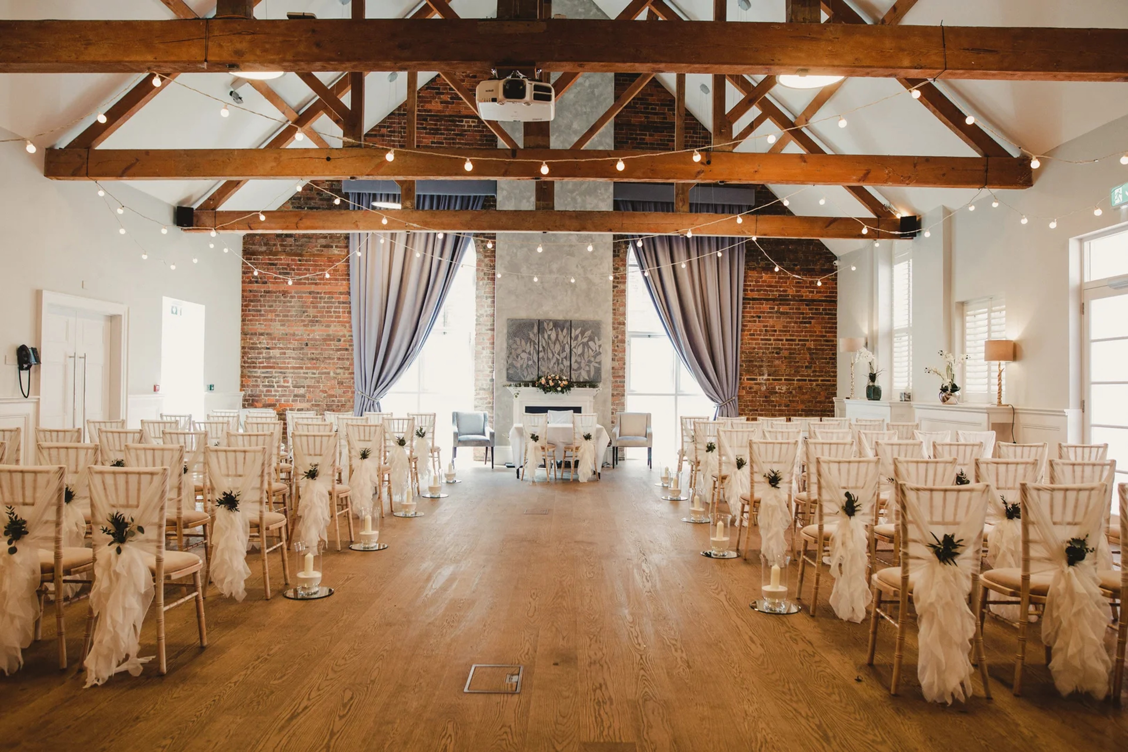Beautiful ceremony room with exposed brick, wooden beams and festoon lights