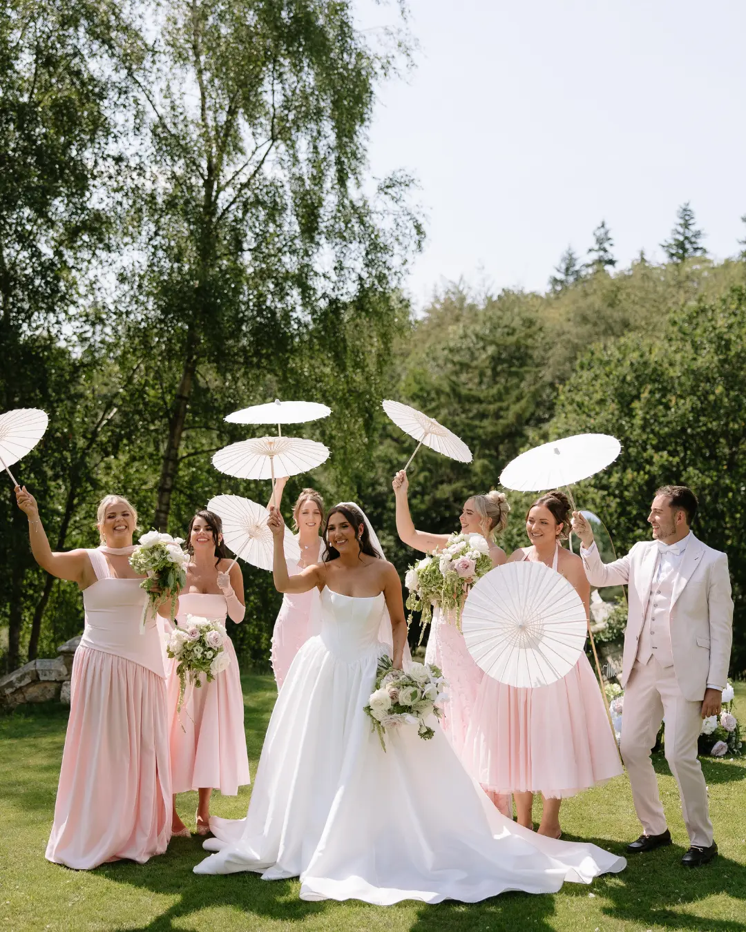 Wedding party with parasols in the gardens at Salomons Estate