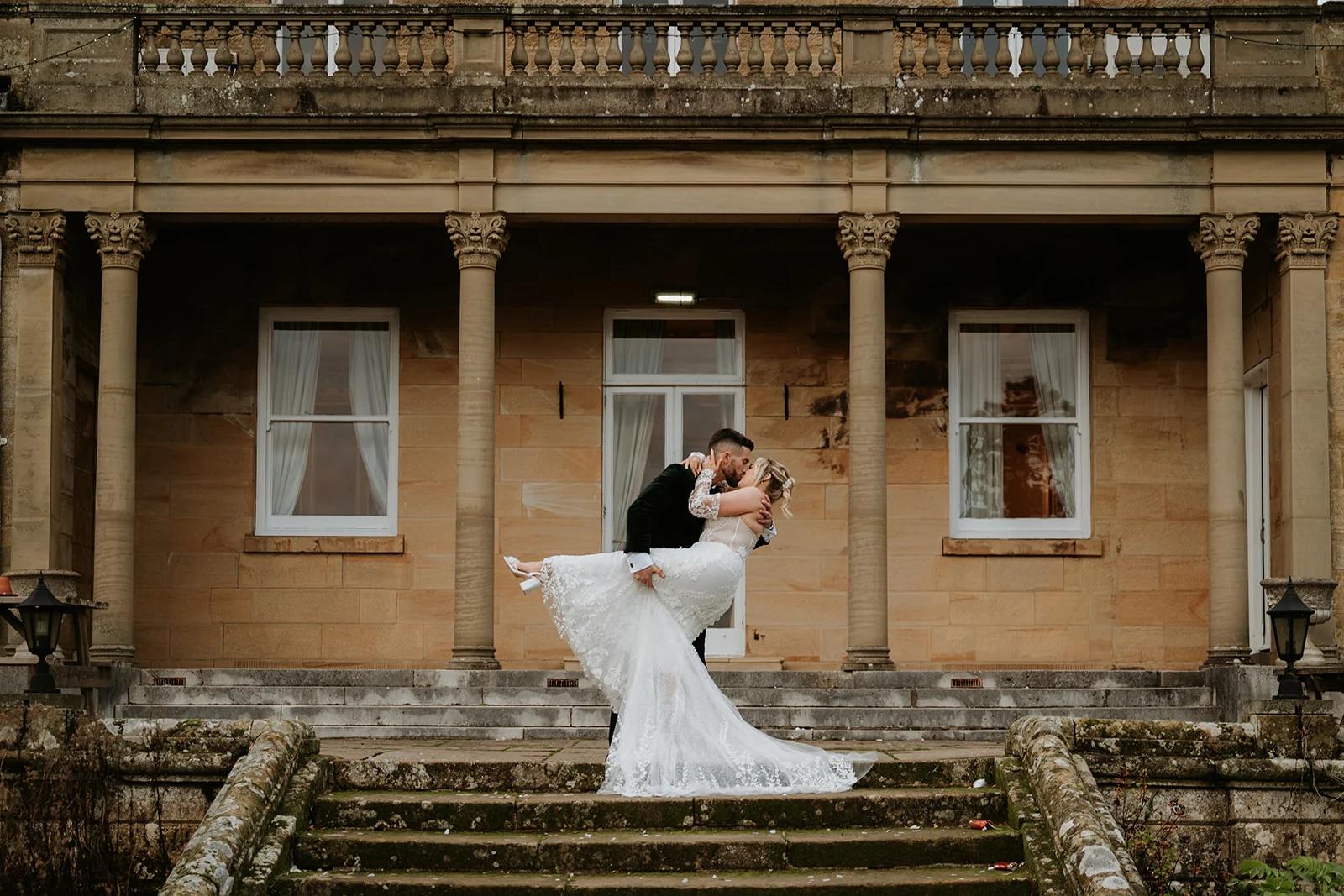 Groom lifting bride on the steps of Salomons Estate
