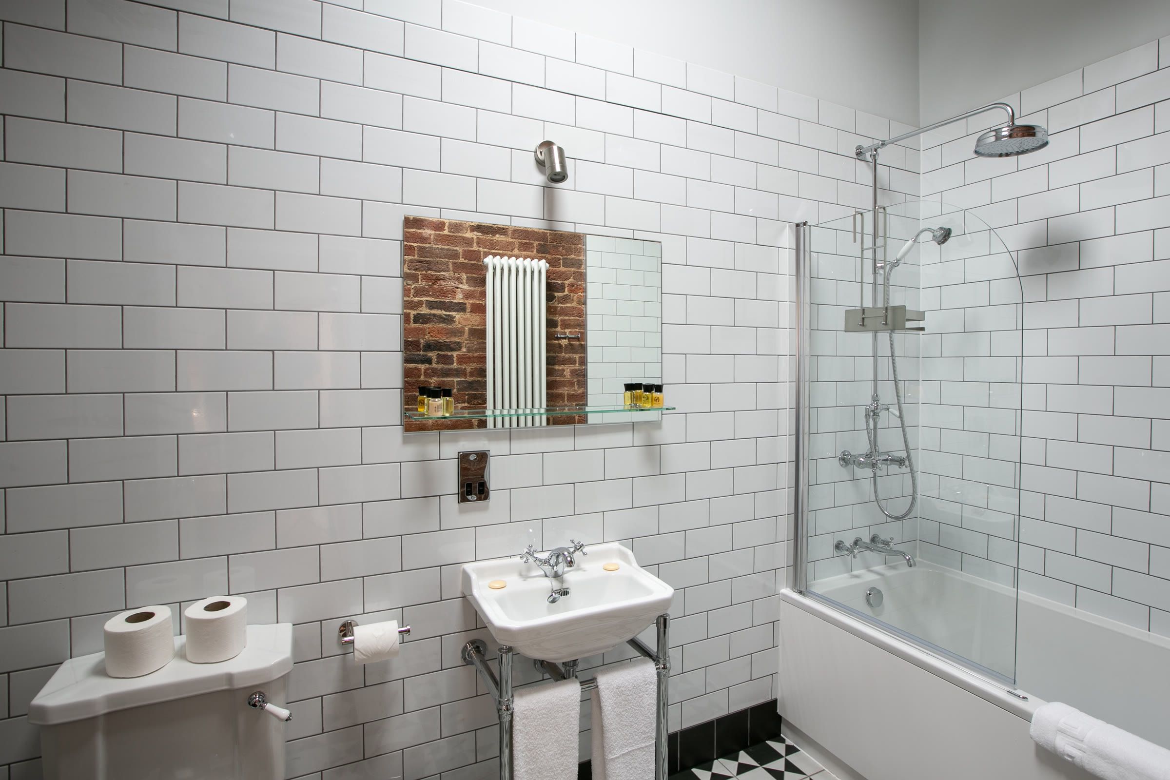 Bathroom with a shower over the bath, metro tiles and a period basin in a Garden Cottage at Salomons Estate