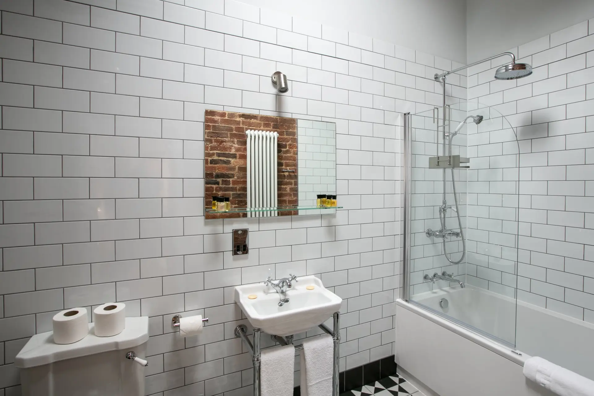 Bathroom with a shower over the bath, metro tiles and a period basin in a Garden Cottage at Salomons Estate
