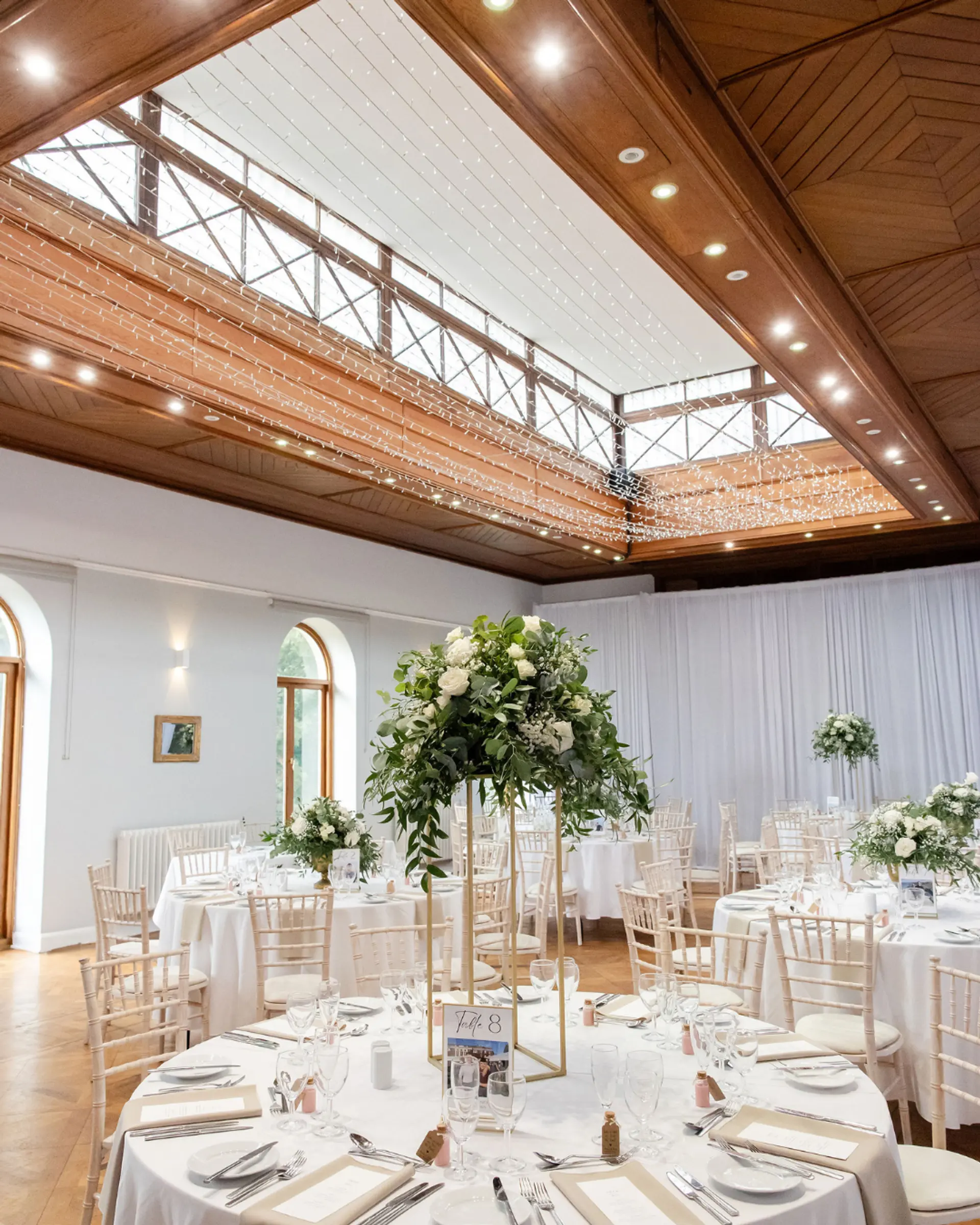 Wedding breakfast tables beneath fairy lights in the Theatre at Salomons Estate