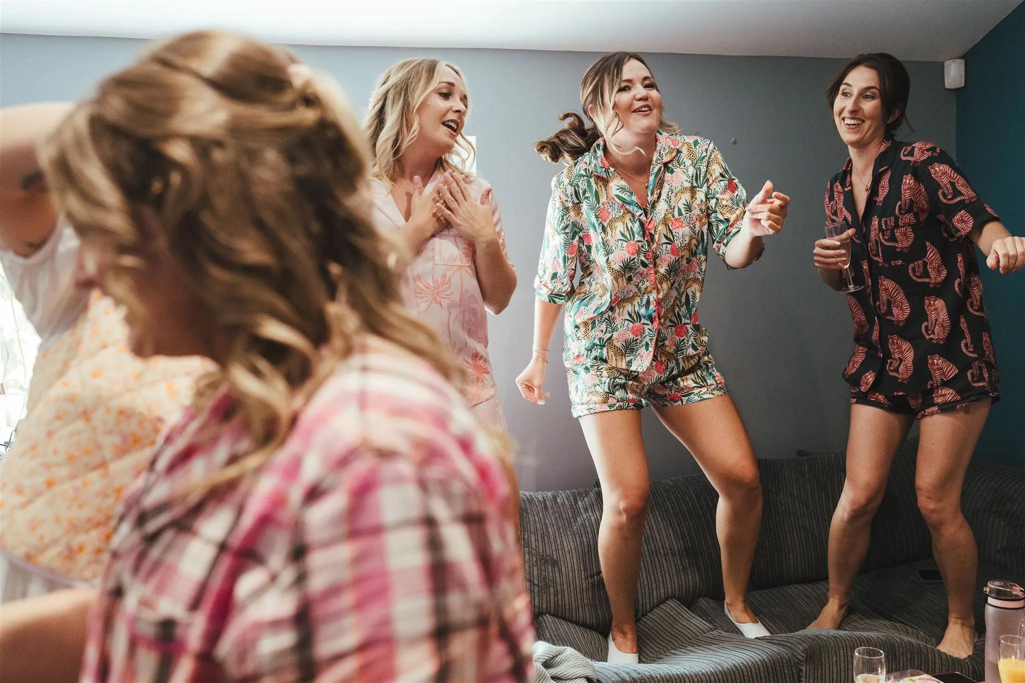 Friends dancing together in matching pyjamas at a hen party at Salomons Estate