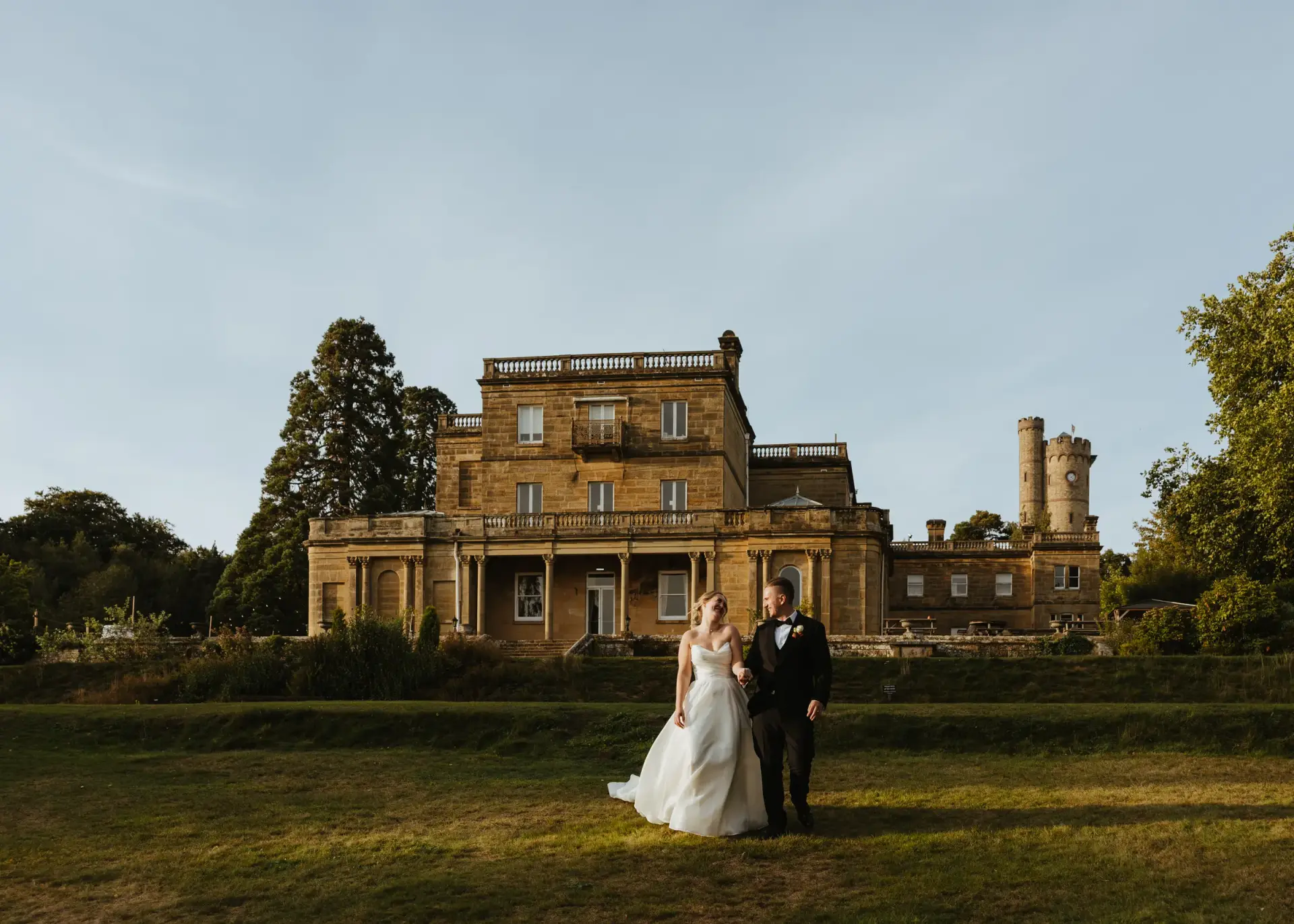 Bride and groom on the lawn in front of Salomons Estate at golden hour