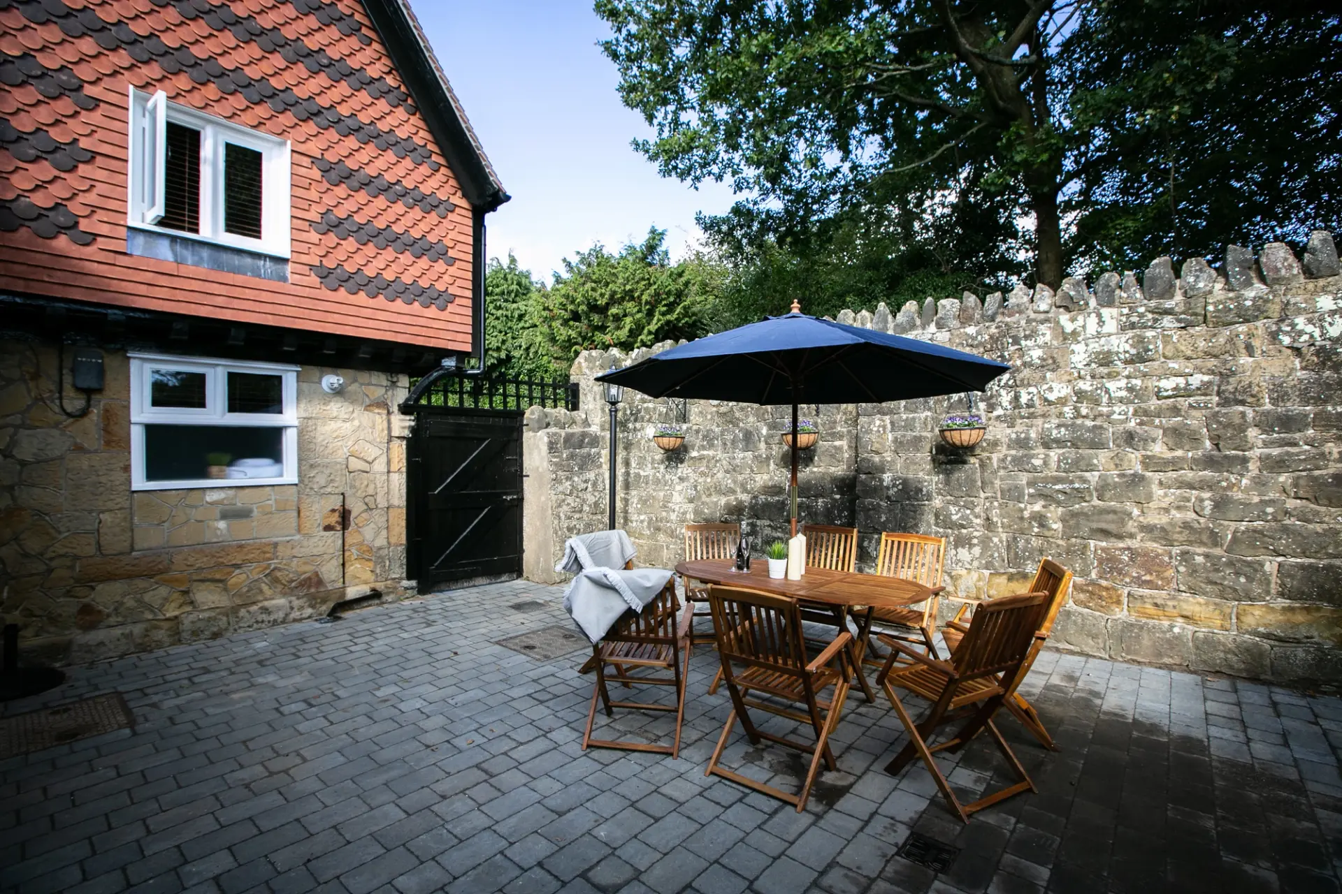 Private walled courtyard with outdoor dining table and parasol at The Cottage, Salomons Estate