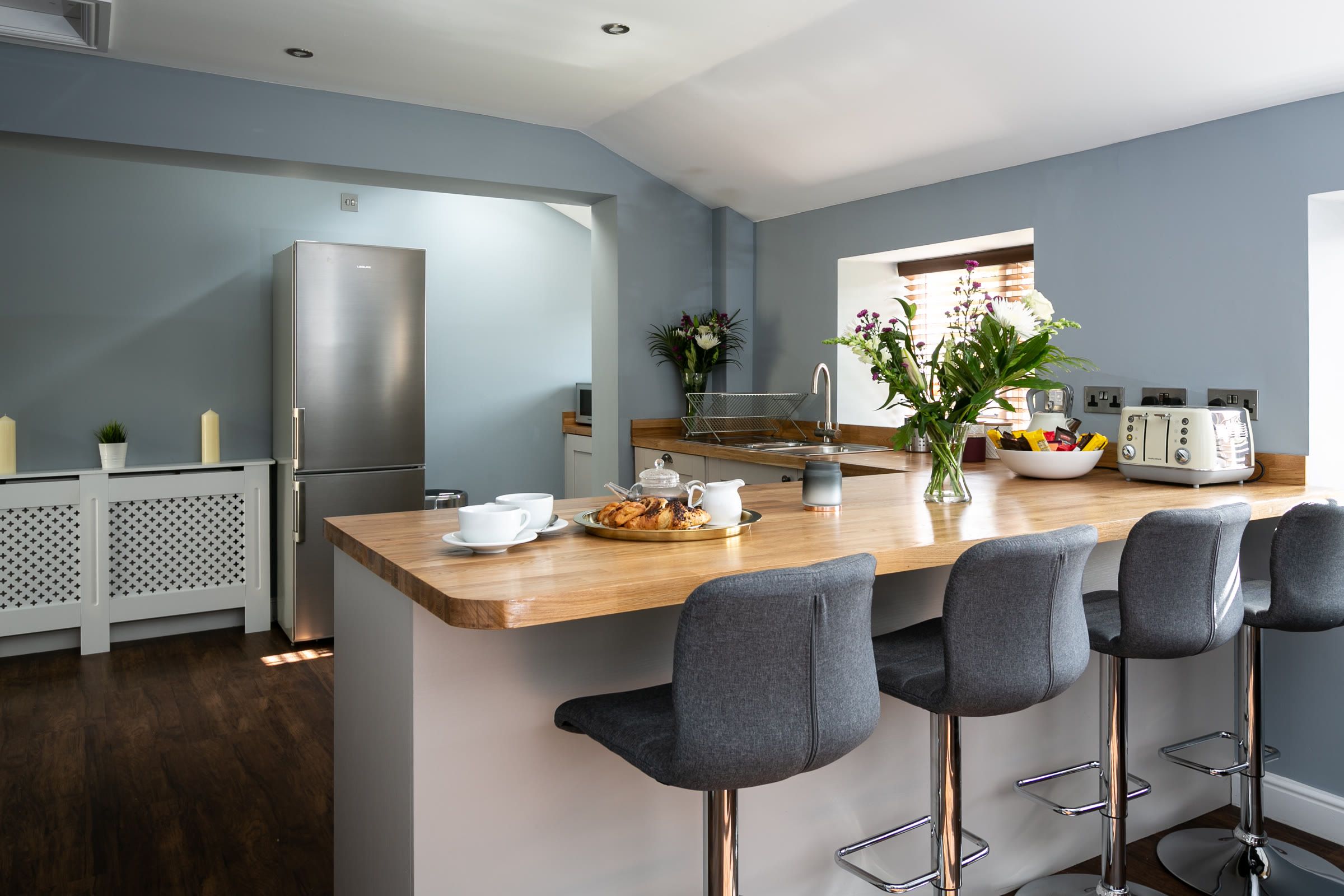 Open plan kitchen with a wooden breakfast bar and bar stools at The Cottage, Salomons Estate