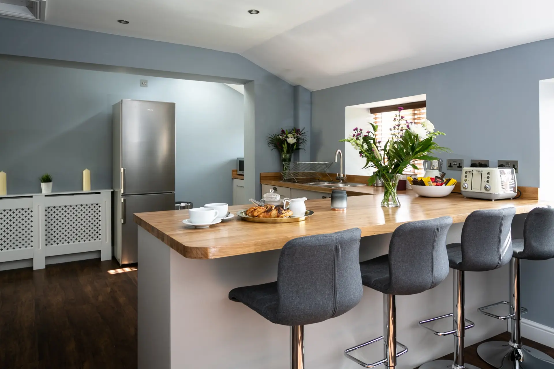 Open plan kitchen with a wooden breakfast bar and bar stools at The Cottage, Salomons Estate
