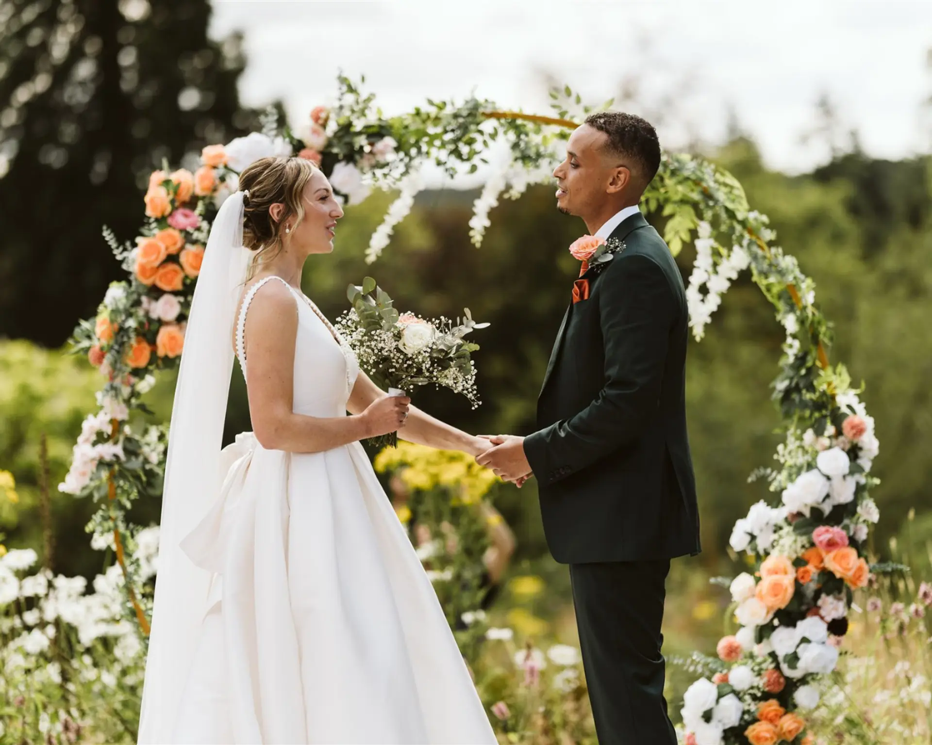 Bride and groom exchanging vows beneath a floral arch in the Salomons Estate gardens