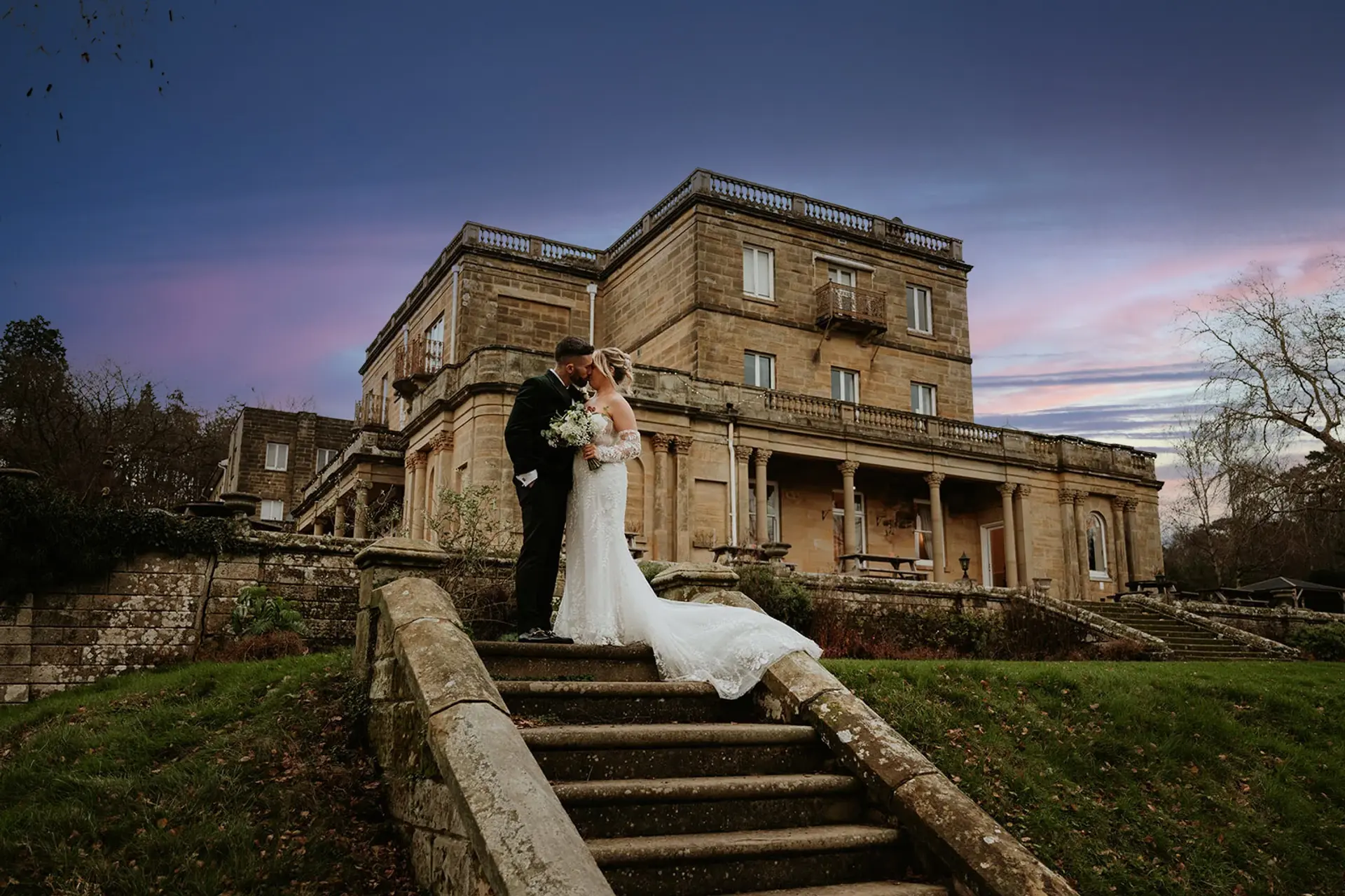 Bride and groom on the estate steps at dusk in front of Salomons Estate