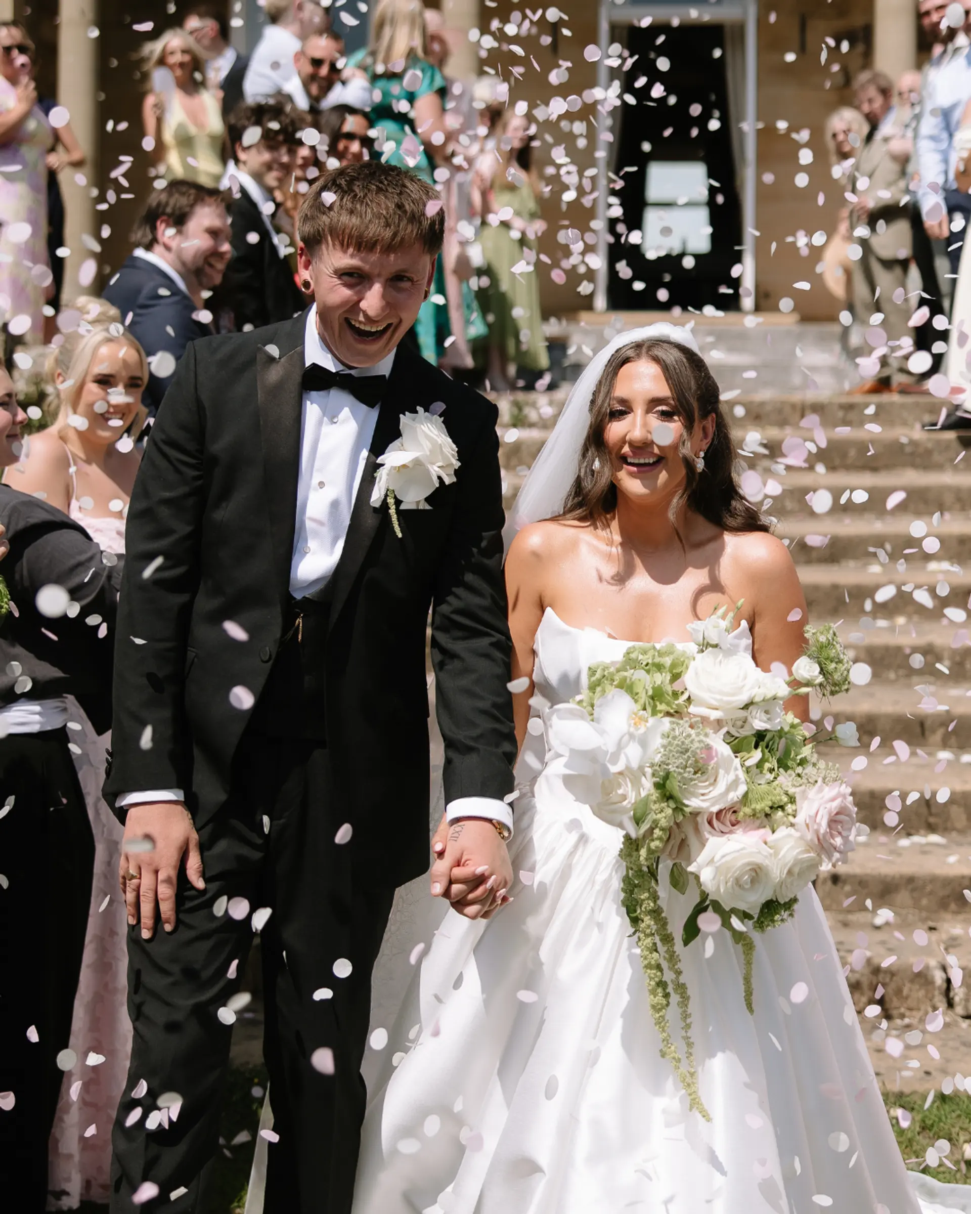 Newly married couple walking through confetti outside Salomons Estate