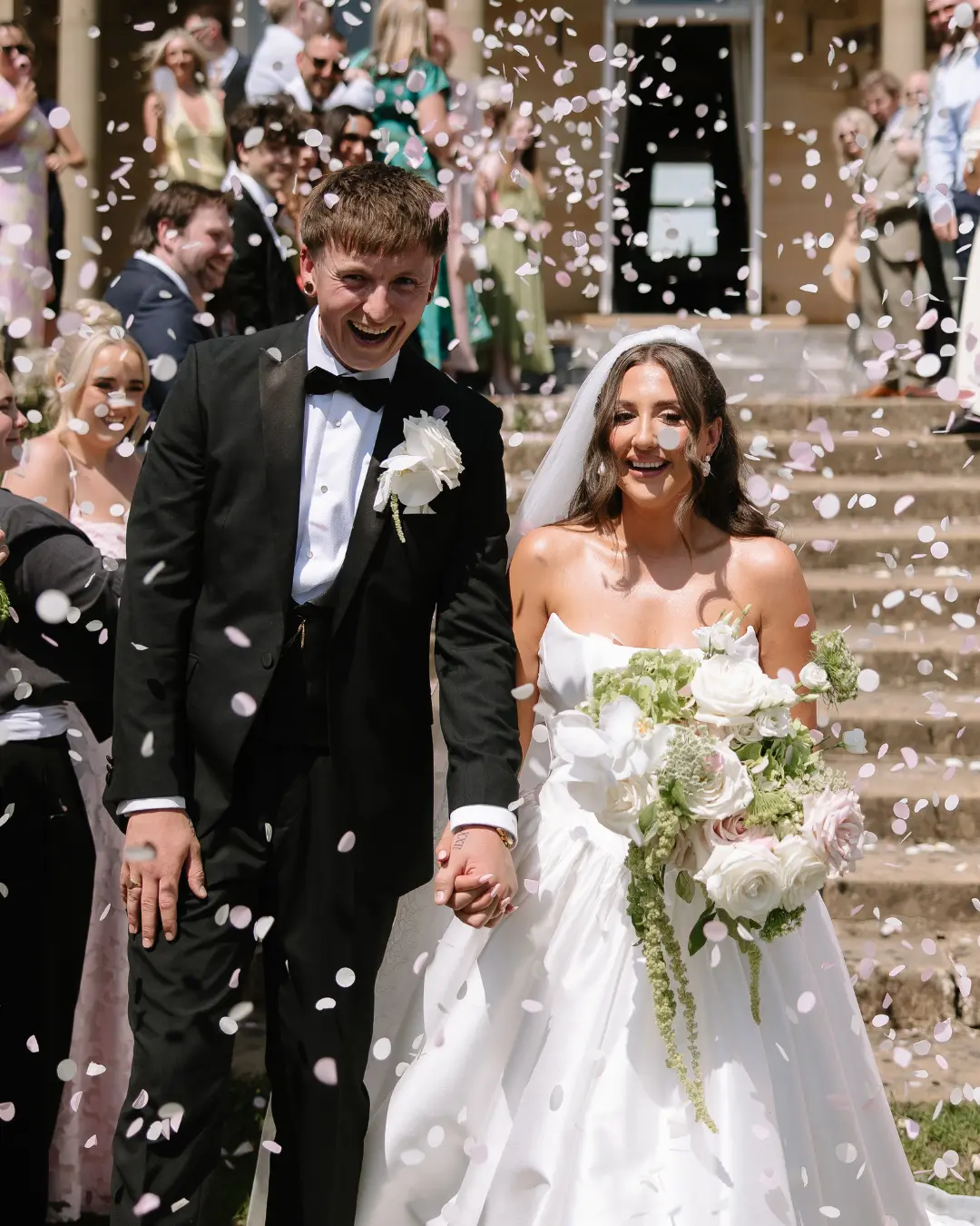 Newly married couple walking through confetti outside Salomons Estate
