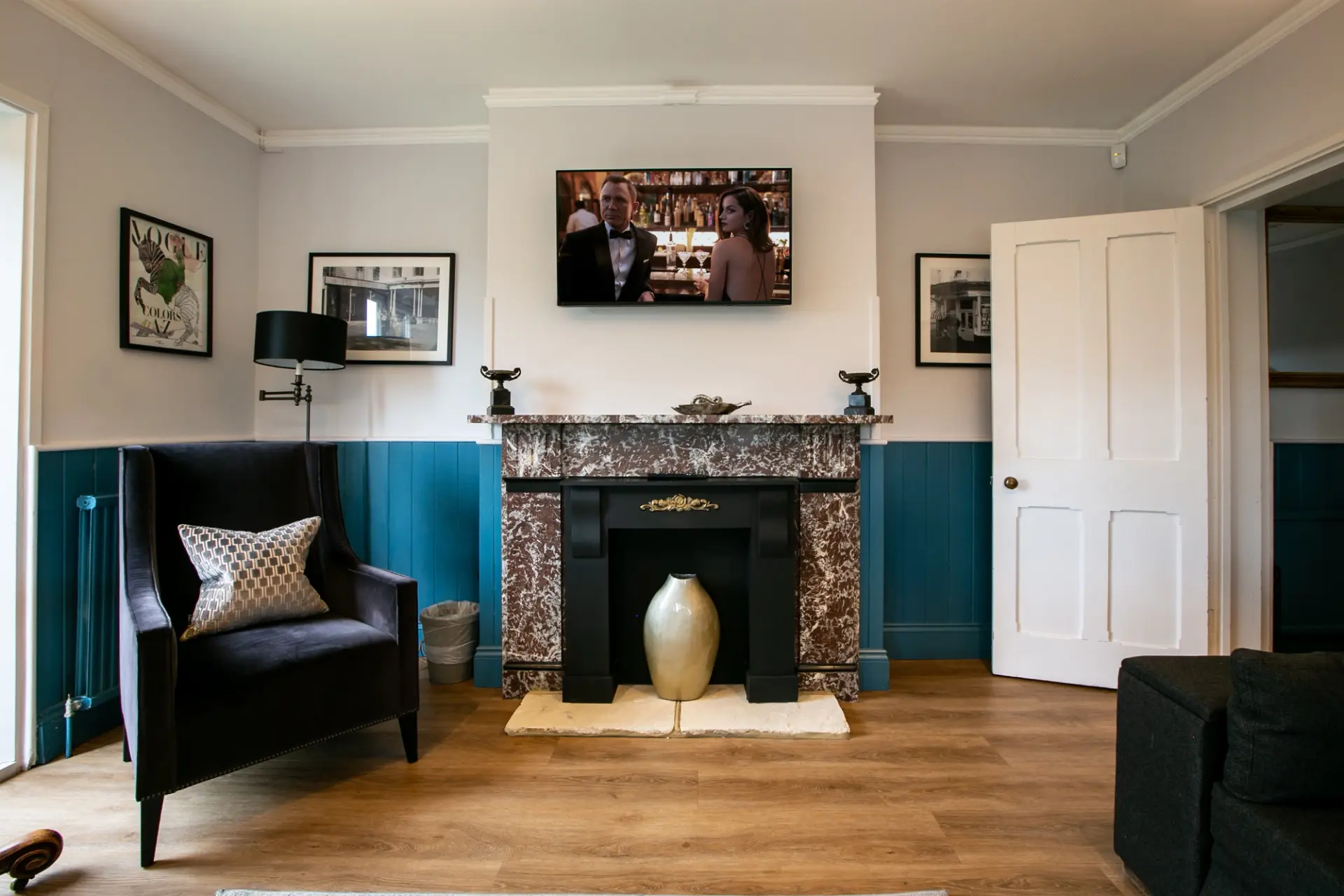 Snug with a marble fireplace, armchair and wall-mounted television in The Gatehouse at Salomons Estate