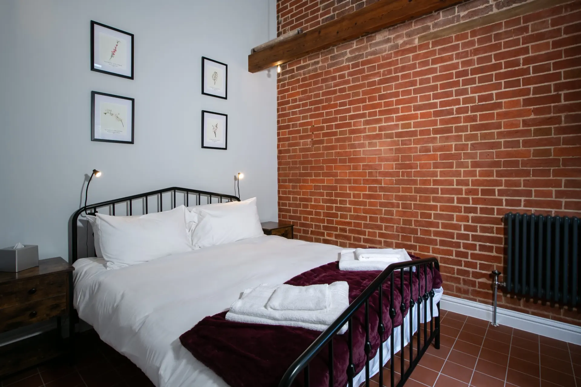 Double bedroom with an exposed brick wall and cast iron radiator in a Garden Cottage at Salomons Estate