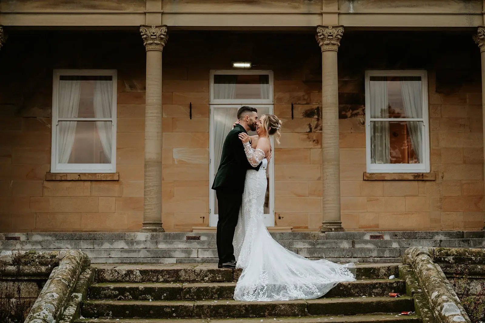 Wedding couple kissing on the veranda steps at Salomons Estate