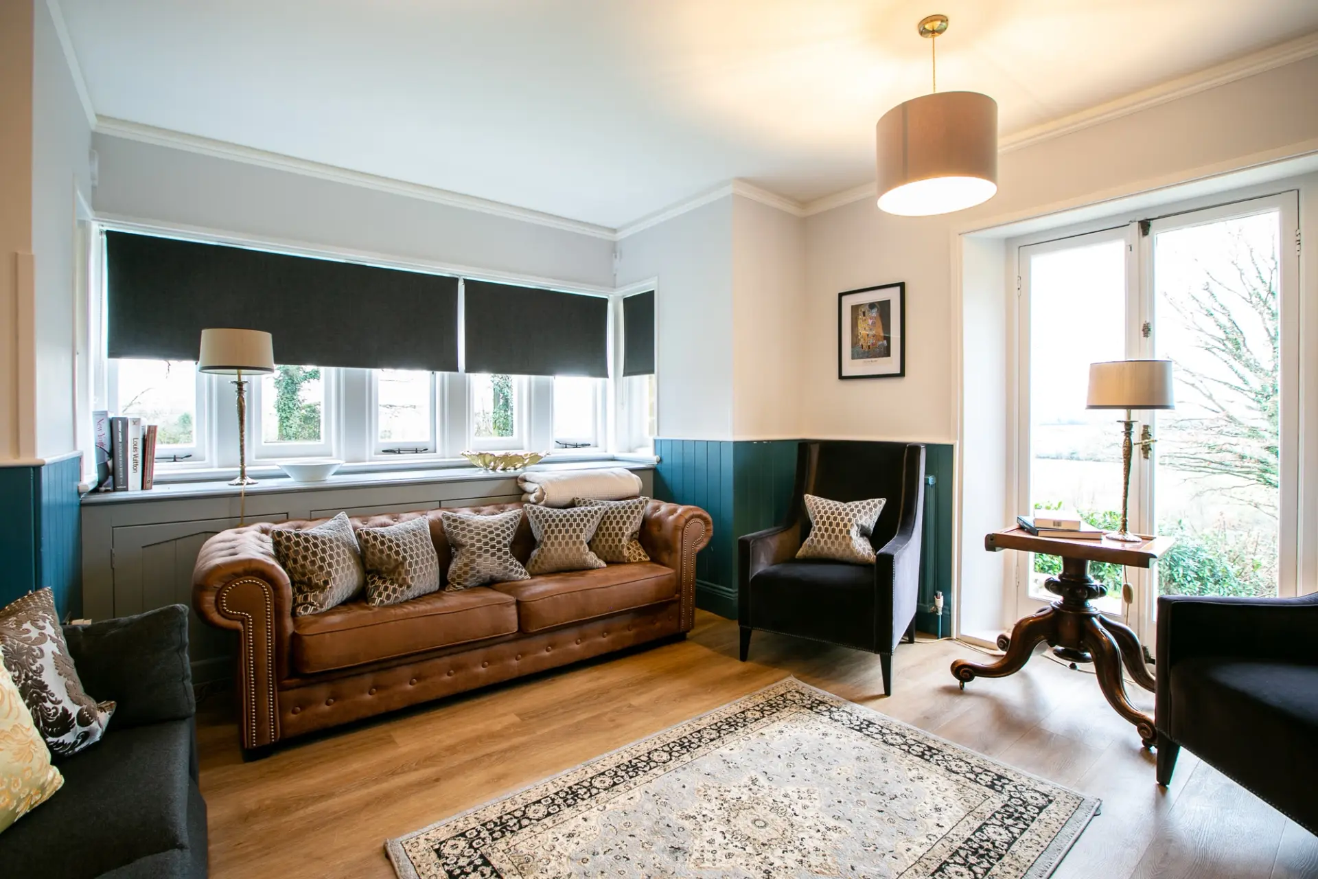 Lounge with a leather Chesterfield sofa and bay window in The Gatehouse at Salomons Estate