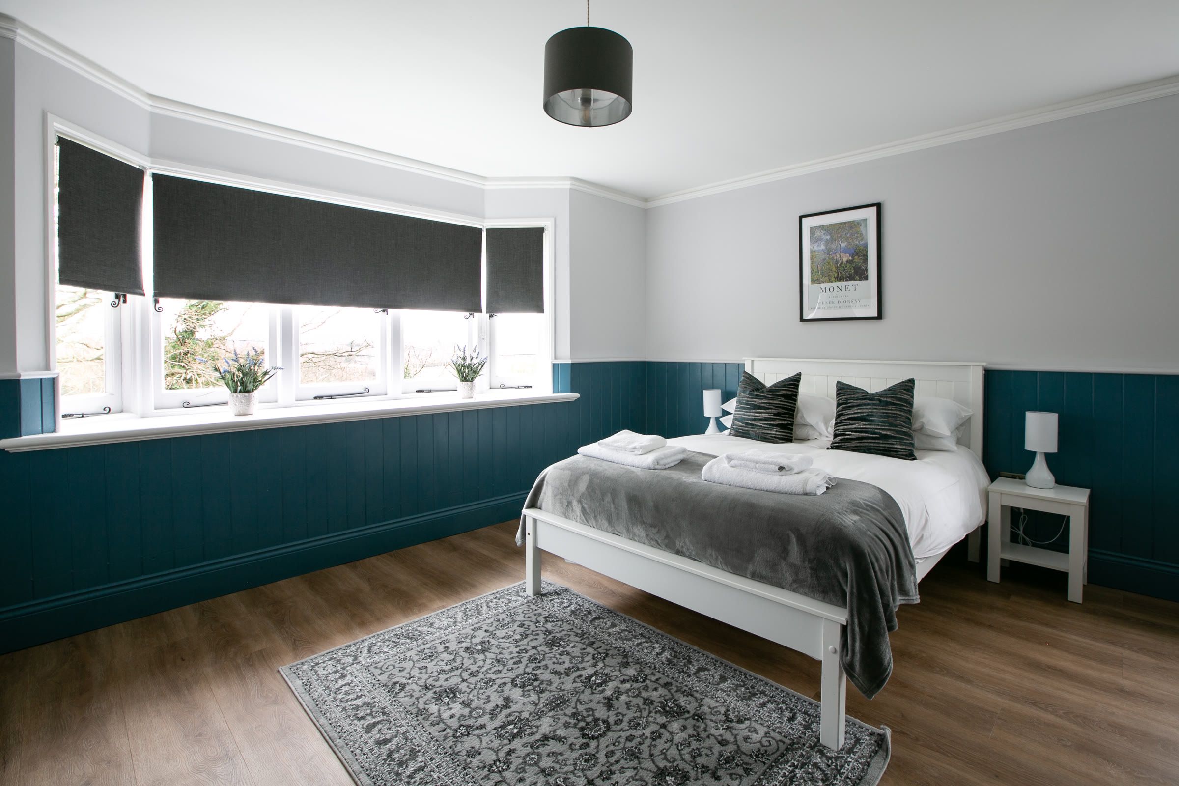 Double bedroom with panelled walls and a bay window in The Gatehouse at Salomons Estate