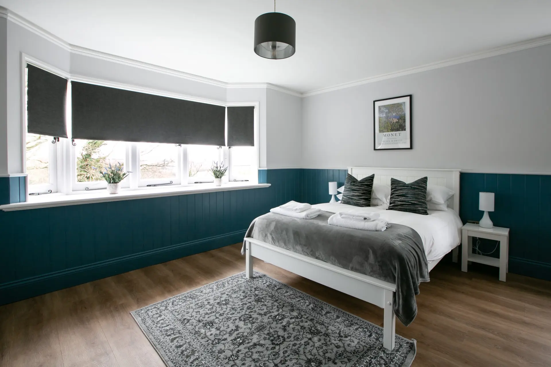 Double bedroom with panelled walls and a bay window in The Gatehouse at Salomons Estate