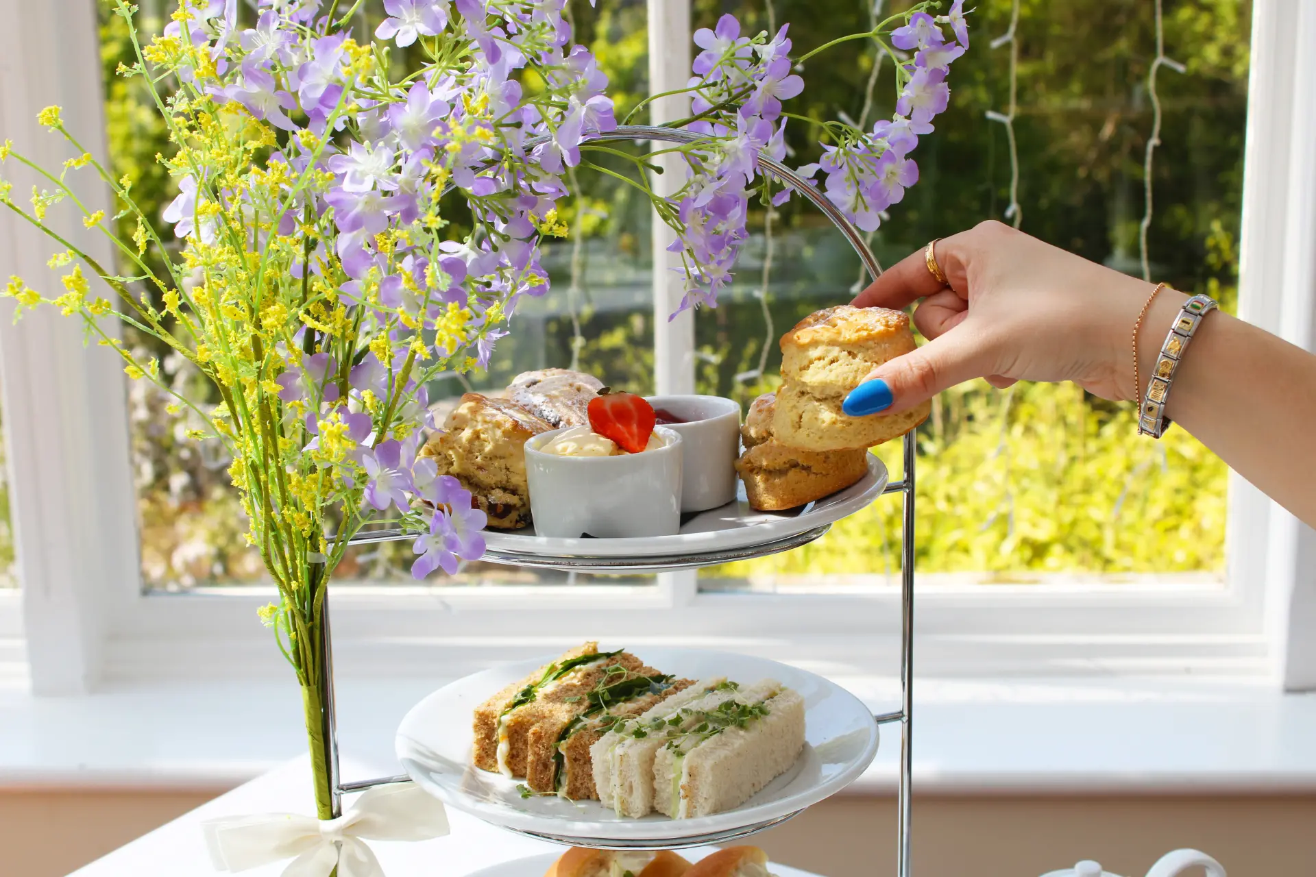 Guest reaching for a freshly baked scone from the afternoon tea tier at Salomons Estate