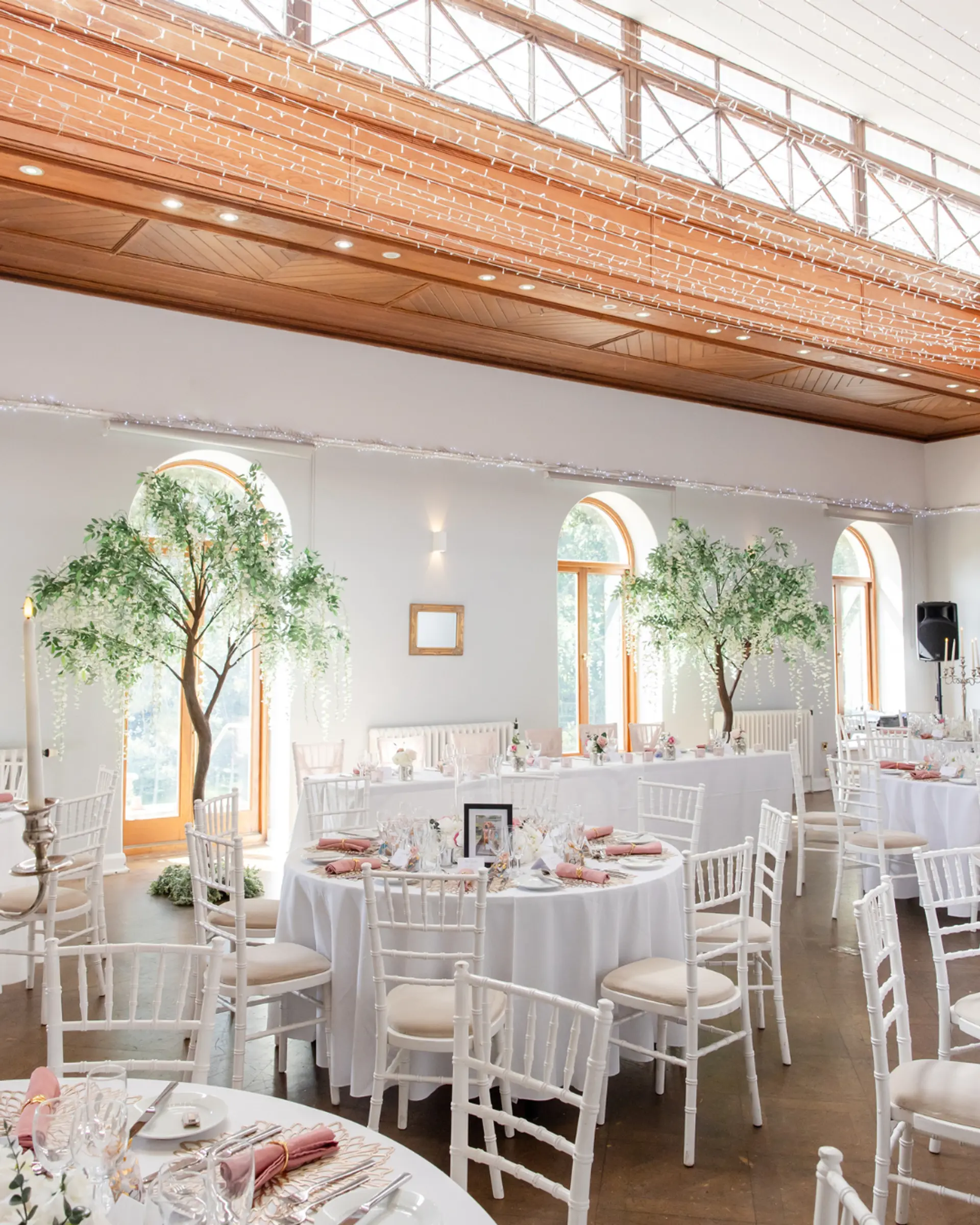 Wedding breakfast setup with floral trees in the Theatre at Salomons Estate