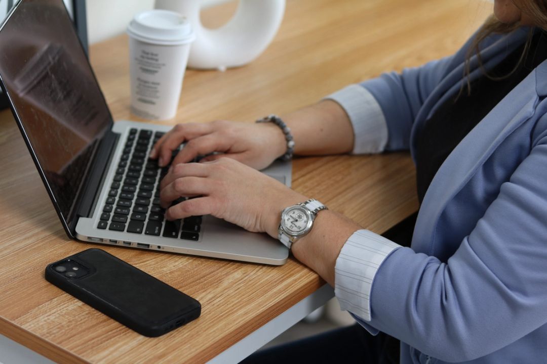 Stephanie is at her laptop working with coffee and her phone getting approvals for clients and their mortgage needs