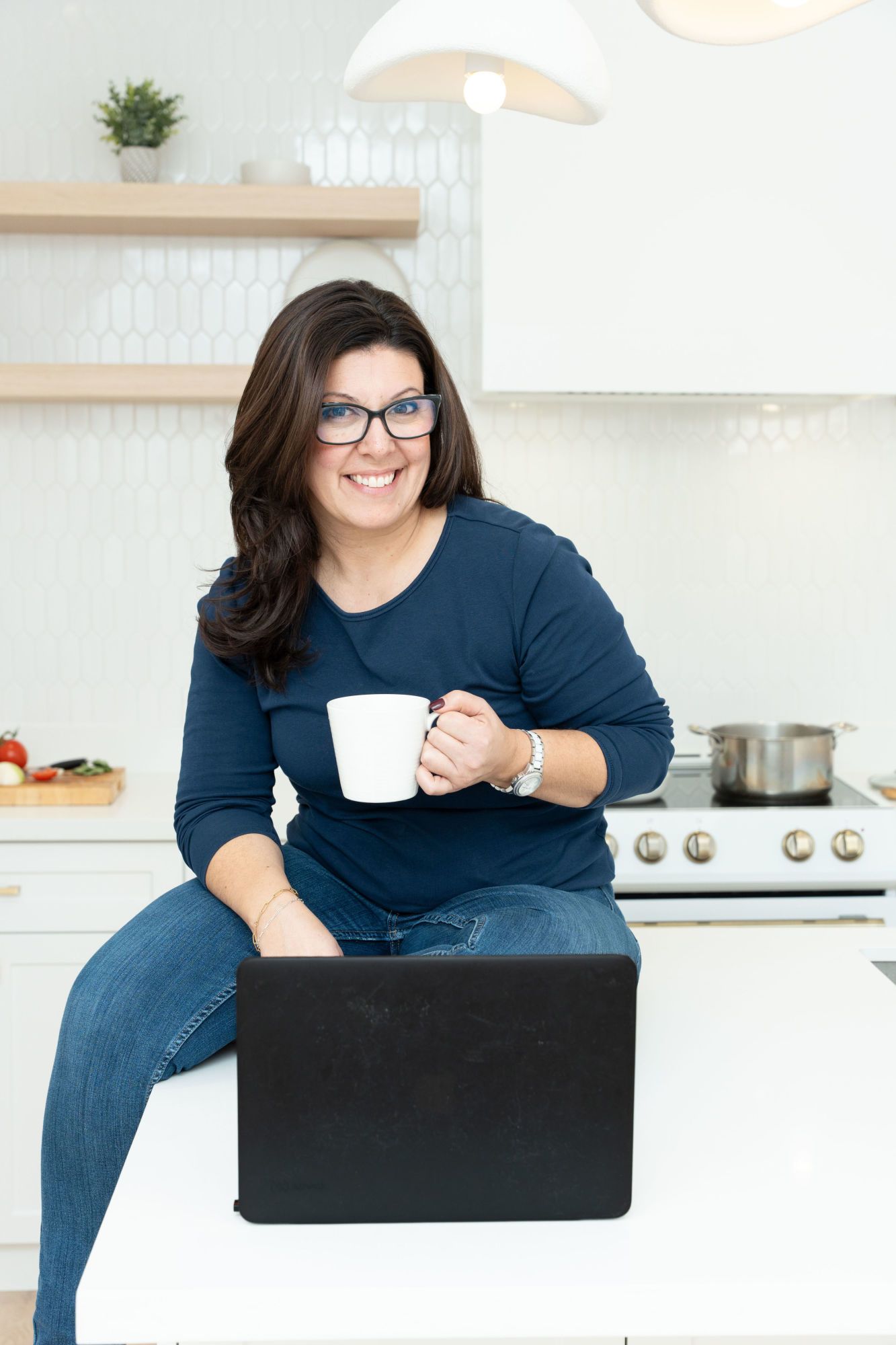 Stephanie is sitting, working on her laptop, drinking coffee