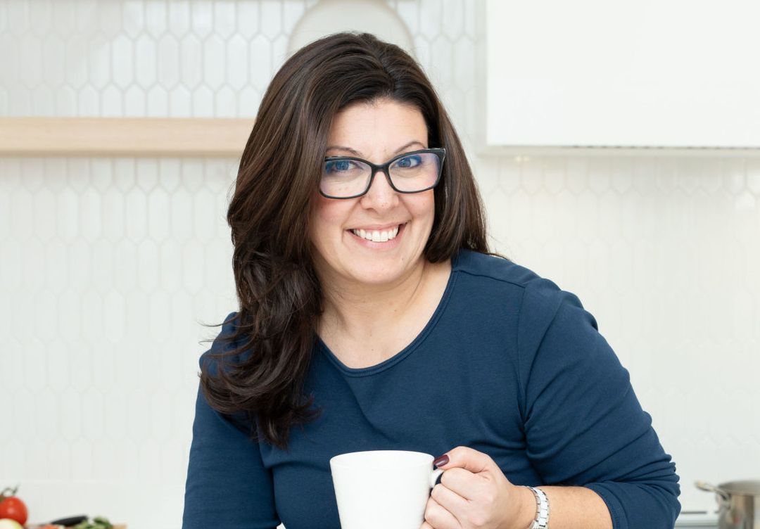 Stephanie is sitting, working on her laptop, drinking coffee